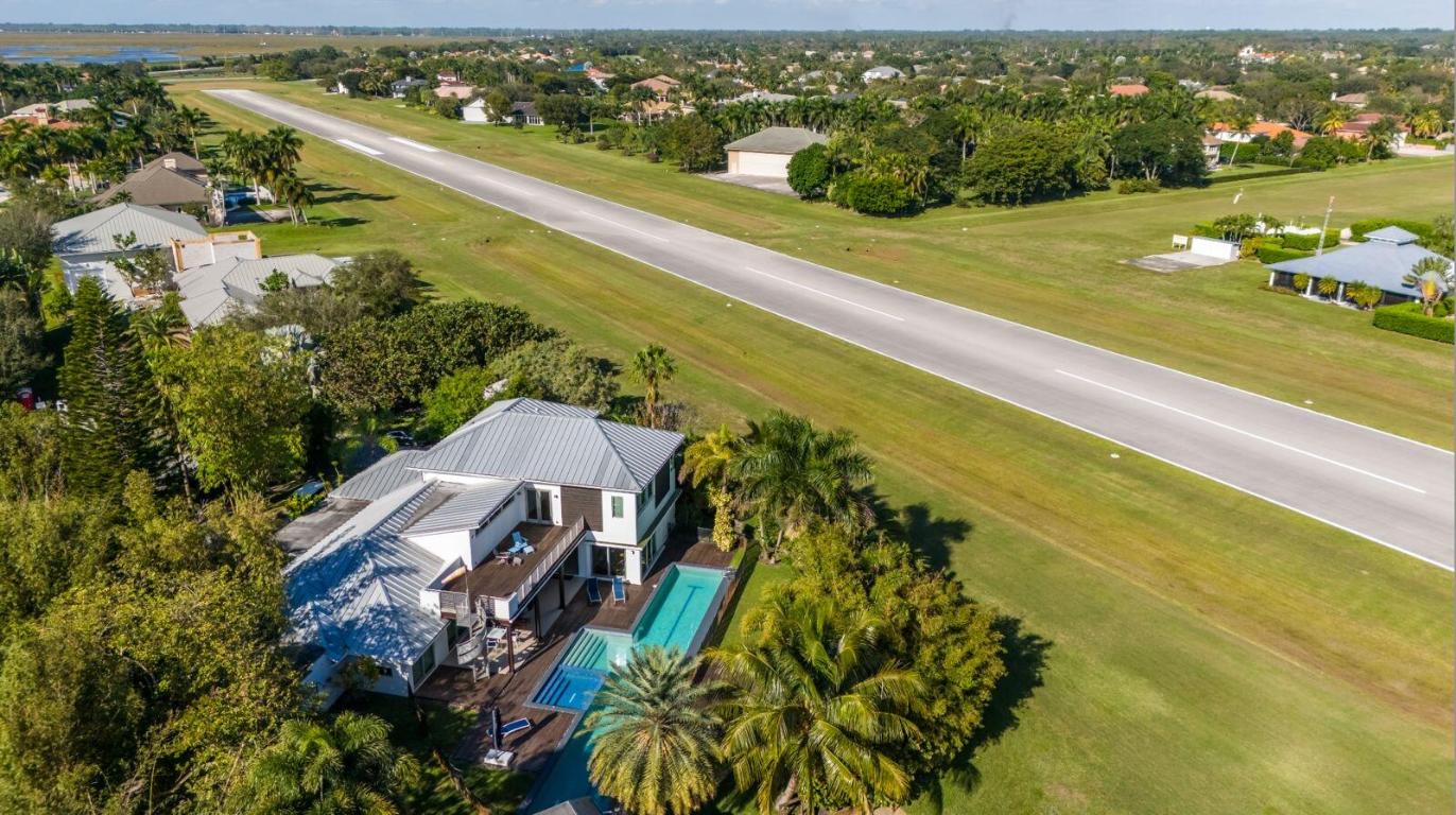Custom estate home located directly on the runway of South Florida's premier aeronautical community. This 5,427 sq ft home is brimming with one-of-a-kind details seamlessly blending modern architecture with luxurious living. Each room was designed to highlight the ample natural light, high celling's, and open floorplan, creating an effortless layout throughout the home. Featuring 5 oversized bedrooms with en-suite baths and a detached guesthouse. The second story offers a primary suite with dual walk-in closets, a spa-inspired bathroom, and a private terrace overlooking the runway and pool. The gourmet kitchen is ideal for entertaining from the large island housing an oversized gas range, Sub-Zero refrigerator, separate prep area with double dishwashers, and a wine room. The amenities continue outdoors with a lap pool, dual heated jacuzzi, a Brazilian teak patio, and a cabana bath.

Just steps away from the home is a 56'W × 46'd hangar (44'w × 14' high door opening). There is additional airplane parking on the 50'×50' concrete ramp. Located on over an 1+/- acre lot, this property is complete with impact glass and a metal roof.

In addition a new Project for upgrading the existing hangar is available.

Property Features:
-Built in 2015
-Custom designed home inspired on modern architecture
-5 bedrooms all complete with en-suite bathrooms
-Detached guest house used as gym or guest bedroom
- 83' Lap pool
-Top of the line construction materials, appliances, and finishes throughout
- Natural light, high ceilings, and open floor plan
- 56'W × 46'd hanger (possibility to expand up to 90' X 50') project available.

The Aero club:
- Located within a mile of Wellington's top equestrian venues
- Private luxury aeronautical community
- 4,000' paved & lit runway
-On-site availability of AV gas & jet fuel at cost