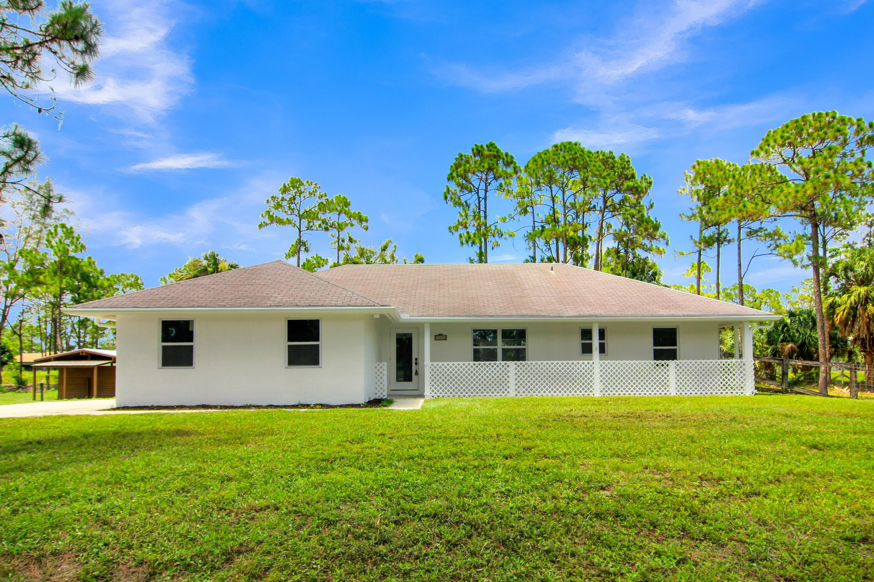 Welcome to this beautifully renovated 3-bedroom single-family home featuring a large air-conditioned family room, nestled on 1.29 fully fenced acres with NO HOA! The property also includes a separate metal-roof covered shed area on the side of the home, ideal for horses, cattle, pets, equipment storage, or a future ADU (subject to county approval). Step inside to discover a bright, open floor plan featuring vaulted ceilings, recessed lighting, updated ceiling fans, and impact windows and doors throughout for added security, hurricane protection, and energy efficiency. Enjoy year-round comfort with a brand-new A/C system featuring a Nest smart thermostat, along with a new water filtration system and upgraded water pump.  The beautifully renovated kitchen is the heart of the home, showcasing quartz countertops, stainless-steel appliances, and contemporary finishes that are perfect for everyday living and entertaining. The brand-new bathrooms have been tastefully redesigned with stylish fixtures and modern finishes. Outside, the fully fenced 1.29-acre lot provides endless possibilities with plenty of room for boats, RVs, trailers, work vehicles, horses, livestock, pets, gardening, or creating your own private outdoor retreat—all without the restrictions or monthly fees of an HOA. This unique property offers the space, flexibility, and freedom you've been looking for.