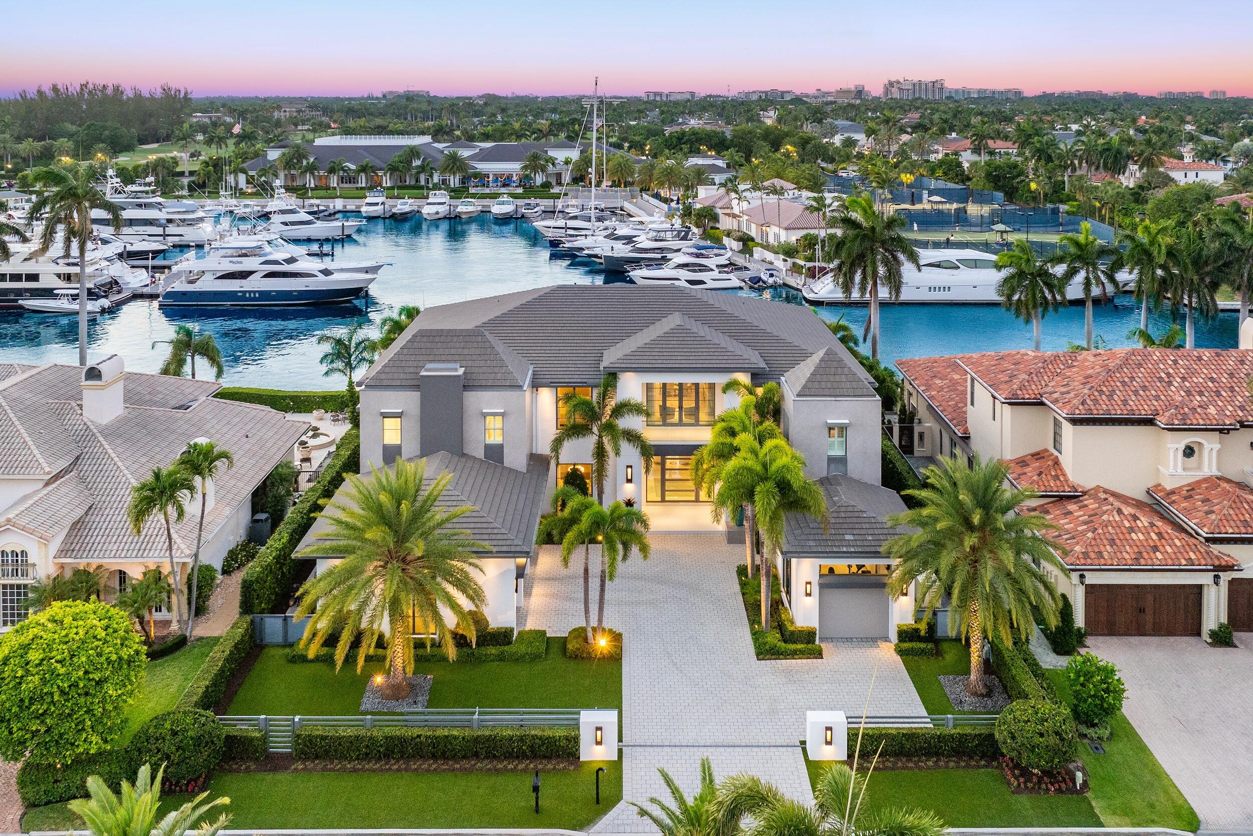Welcome to 169 W. Key Palm Road in Boca Raton, a visionary display of architectural intrigue and soft contemporary design. The waterfront property is situated behind private gates in one of the most prominent residential communities in all of South Florida--Royal Palm Yacht & Country Club. If its luxurious finishes, open spaces and sophisticated palette weren't already enough to set an inviting tone, the estate also dazzles with dramatic sunsets that add to a breathtaking panoramic canvas--one that includes views of the prestigious Royal Palm Yacht & Country Club marina. Perched on a safe and well-protected bay, with ocean access only minutes away, the estate boasts 104 feet of deep-water dockage, providing boating enthusiasts with ample room to host a megayacht. Lush landscaping, a stylish infinity-edge pool, a full summer kitchen, a spacious entertainment area, and dramatic nighttime lighting add to the rich exterior ambience. 169 W. Key Palm Road, completed in 2021, encompasses 8,975 square feet of living space and 11,858 square feet overall. 

The six-bedroom layout (with six baths and two half baths) also features a stately living room, family room, club room, and a formal dining room. Rooms cast in brilliant whites and natural hues lend an air of elegance to spaces complemented by polished marble and rich wood flooring, soaring ceilings, and dazzling lighting fixtures throughout that double as original works of modern art. A towering marble wall designed with a see-through inset fireplace divides the living spaces. On one side, there's a glamorous seating area; on the other, there's a bar that recalls the intimate cocktail counters at a five-star restaurant, a cozier seating area, and enough room for a pool table. An exquisitely designed office space features an abundance of privacy and natural light. The sprawling chef's kitchen that overlooks the water is a study in sophistication. Once again, brilliant whites set the tone, this time as the hue for custom cabinetry that includes a row of individual display spaces spanning its upper reaches. In addition, the kitchen is designed with world-class appliances, a mammoth marble island, and an adjoining breakfast area. 

The primary suite, with a private balcony overlooking the bay, invites the outdoors inside, bathing the second-floor space in chic serenity. The equally inspired primary bath includes a soaking tub, an oversized shower with plantation shutters, and two boutique-style walk-in closets. The upstairs also features a seating area between the separate wings with arching wood beams that run the length of the spaces leading to the bedrooms. 

The estate, flawlessly executed by the preeminent Mary Widmer Luxury Collection, also has a four-car garage that can accommodate car lifts. This is modern living at its finest--in a community with international renown. Welcome to 169 W. Key Palm Road.