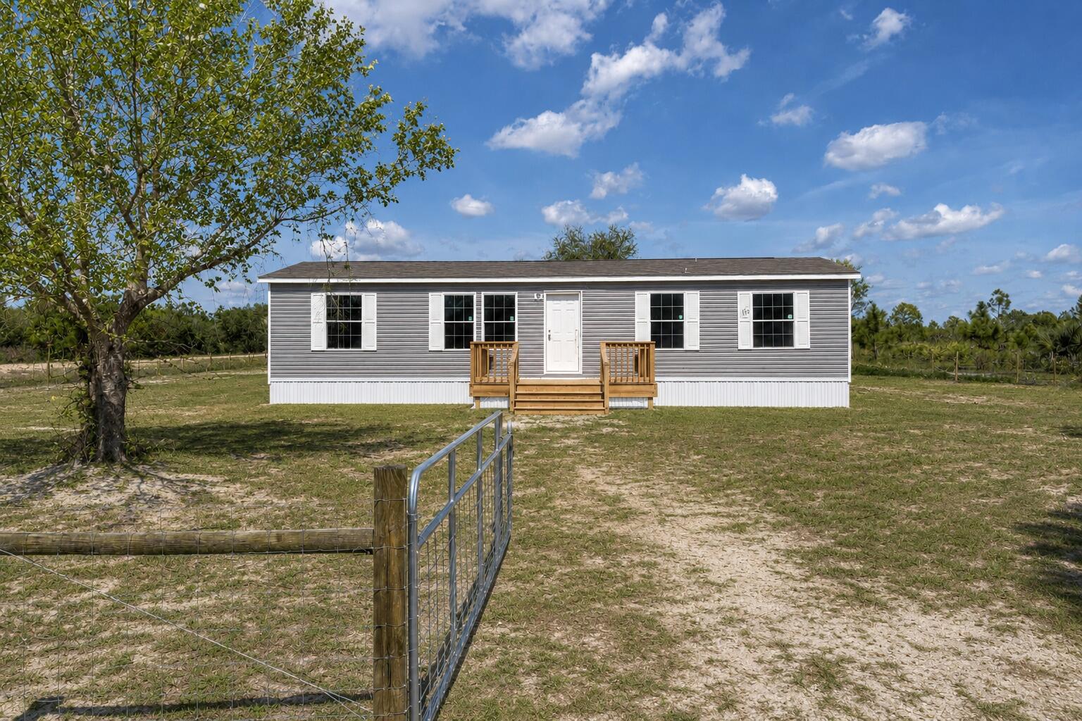Take advantage of this incredible opportunity to own a brand-new 4-bedroom, 2-bath Champion Lake Manor model offering 1,493 sq ft of modern living space. Situated on a fully fenced 1.50-acre corner lot with Residential Agricultural zoning, this property offers both privacy and accessibility on a good, maintained road. Bring your animals, toys, and outdoor plans—there's plenty of room to live the lifestyle buyers are looking for. Inside, you'll find a bright open-concept layout with finished drywall throughout, giving the home a true site-built feel. The split-bedroom floor plan adds privacy, while the spacious kitchen features ample cabinetry and counter space—perfect for everyday living and entertaining. The primary suite offers a private bath and  generous closet space, with additional bedrooms ideal for family, guests, or a home office. This home is move-in ready, never lived in, and includes a full manufacturer warranty for added peace of mind. Fully fenced, new construction, acreage, and incentives—this one stands out. Schedule your showing today!