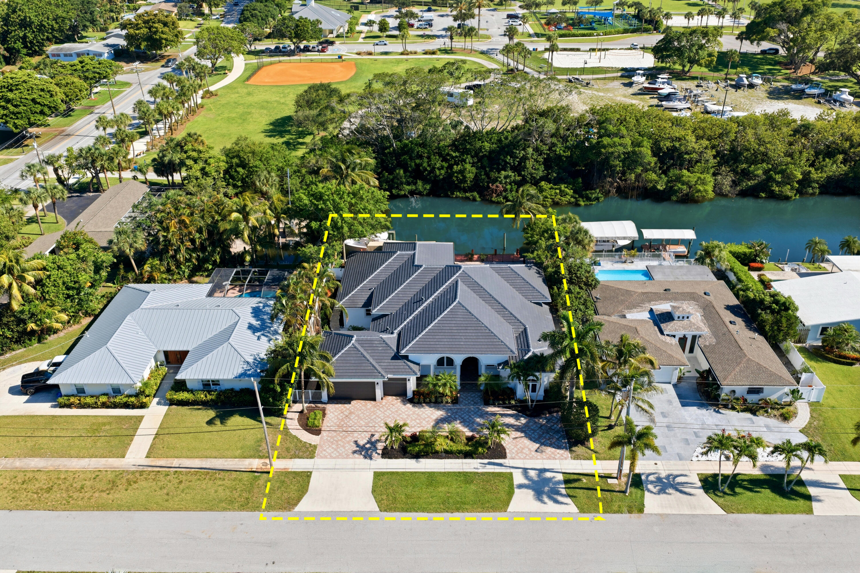 One of the most unique waterfront opportunities available, this exceptional property offers 95 feet of waterfrontage on a rare homesite with no residences built across the canal, creating privacy. Boaters will appreciate the 75-foot dock with newer cap and batter piles, a 12,000-pound Hi-Tide lift with electric pedestal, and fixed-bridge access. Seller may include the boat (31 Grady-White Twin engine 250 Yamaha) with an acceptable offer, making this a true turnkey waterfront lifestyle opportunity. This 4-bedroom, 4-full-bath, and 1-half-bath, 3 car garage residence is thoughtfully designed for both everyday living and entertaining. A grand foyer with chandelier lighting welcomes you into the home, where volume ceilings, travertine flooring, and a natural gas fireplace create a warm and inviting atmosphere. The split-bedroom floor plan offers privacy and functionality, featuring a double-door den with engineered hardwood flooring, recessed lighting, and ceiling fan. The spacious primary suite is a private retreat with luxury vinyl plank flooring, decorative millwork, dual custom walk-in closets, private patio access, and tranquil views of the pool and waterfront. The luxurious primary bath includes dual vanities, a jetted soaking tub, separate shower with dual shower heads, water closet, and abundant linen storage. The gourmet kitchen is equipped with granite countertops, wood cabinetry, an oversized center island, walk-in pantry, GE Monogram natural gas cooktop with center grill, wall oven, built-in microwave, beverage station with wine storage, built-in refrigerator, KitchenAid dishwasher, and a breakfast nook overlooking the outdoor living area. Designed to embrace the Florida lifestyle, the outdoor space features a recently resurfaced and retiled chlorine pool with spillover spa, gas pool heater, Aqualink automation system, pool safety fence, new paver patio, and a covered summer kitchen area and a covered bar area ideal for entertaining. Additional highlights include a new roof (2025), new gutters (2025), spray foam insulation, natural gas service through AmeriGas, gas dryer, central vacuum system, whole-house intercom, plantation shutters, spacious laundry room with utility sink and abundant storage, and generous closet space throughout. Built in 2007 and meticulously maintained, this waterfront residence combines privacy, boating amenities, and exceptional indoor-outdoor living in a truly special setting. Located in the sought-after Village of North Palm Beach, a golf cart-friendly community known for its waterfront lifestyle, community parks, and the acclaimed North Palm Beach Country Club with golf, tennis, dining, and year-round recreational opportunities.