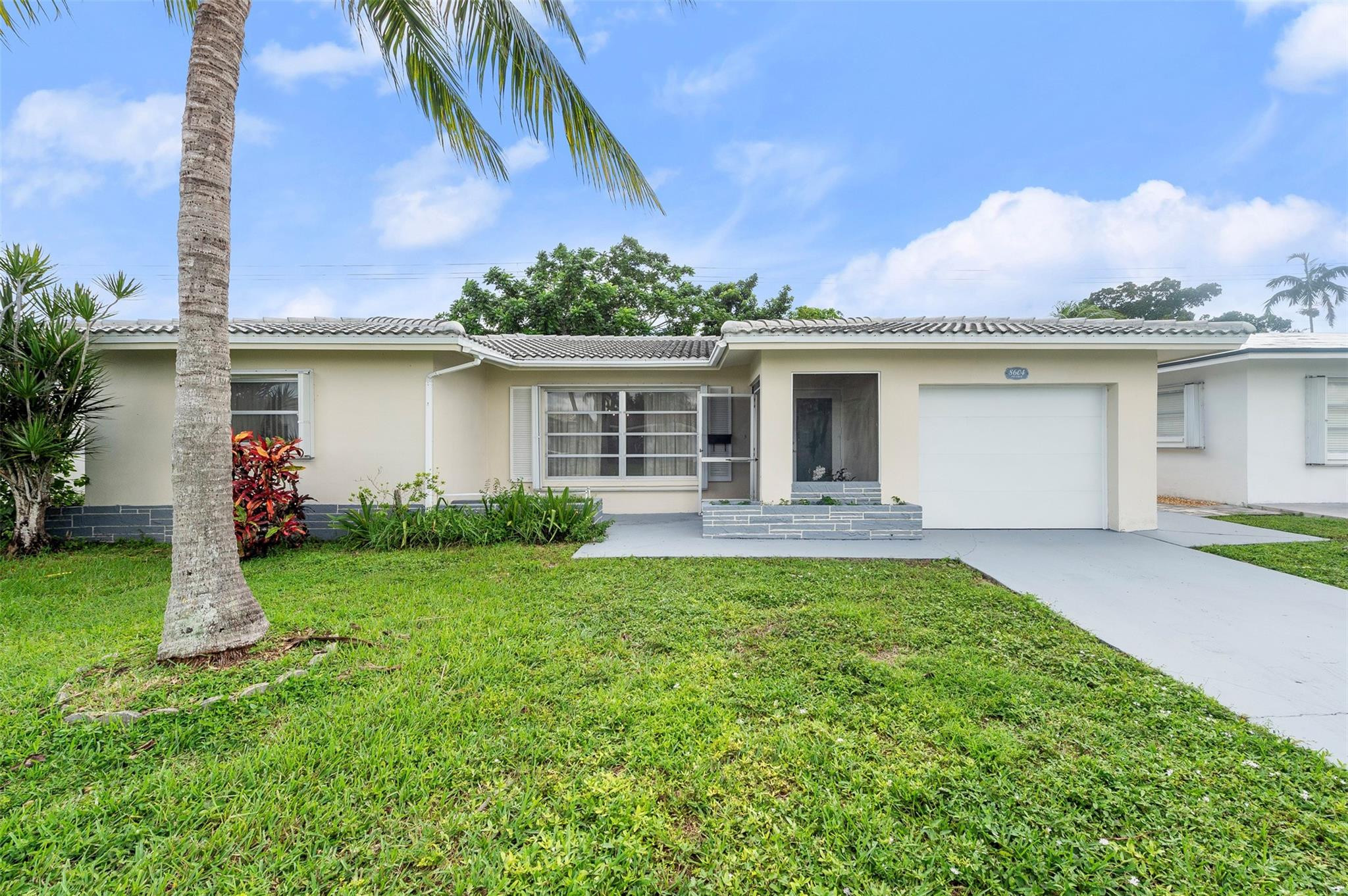 BACK ON THE MARKET! FINANCING FELL THROUGH AND NOW YOU HAVE CHANCE TO MAKE THIS YOUR DREAM HOME!   55 PLUS COMMUNITY. Welcome to your tropical oasis! This charming 2-bedroom, 2-bath home offers comfort, space, and peace of mind with a new impact door, a newer roof (2023), and a 2023 water heater and Newer A/C. The new garage doors and accordion shutters add extra security and value. Inside, you'll find oversized bedrooms and a spacious enclosed Florida room—perfect as a sunroom, office, or easily converted third bedroom. Enjoy indoor-outdoor living in your large backyard surrounded by tropical fruit trees, including mango, soursop, ackee, and June plum. Beautifully maintained home with endless potential!   3% TOWARDS CLOSING COST OR UPGRADES!  YOUR OPPORTUNITY AWAITS!