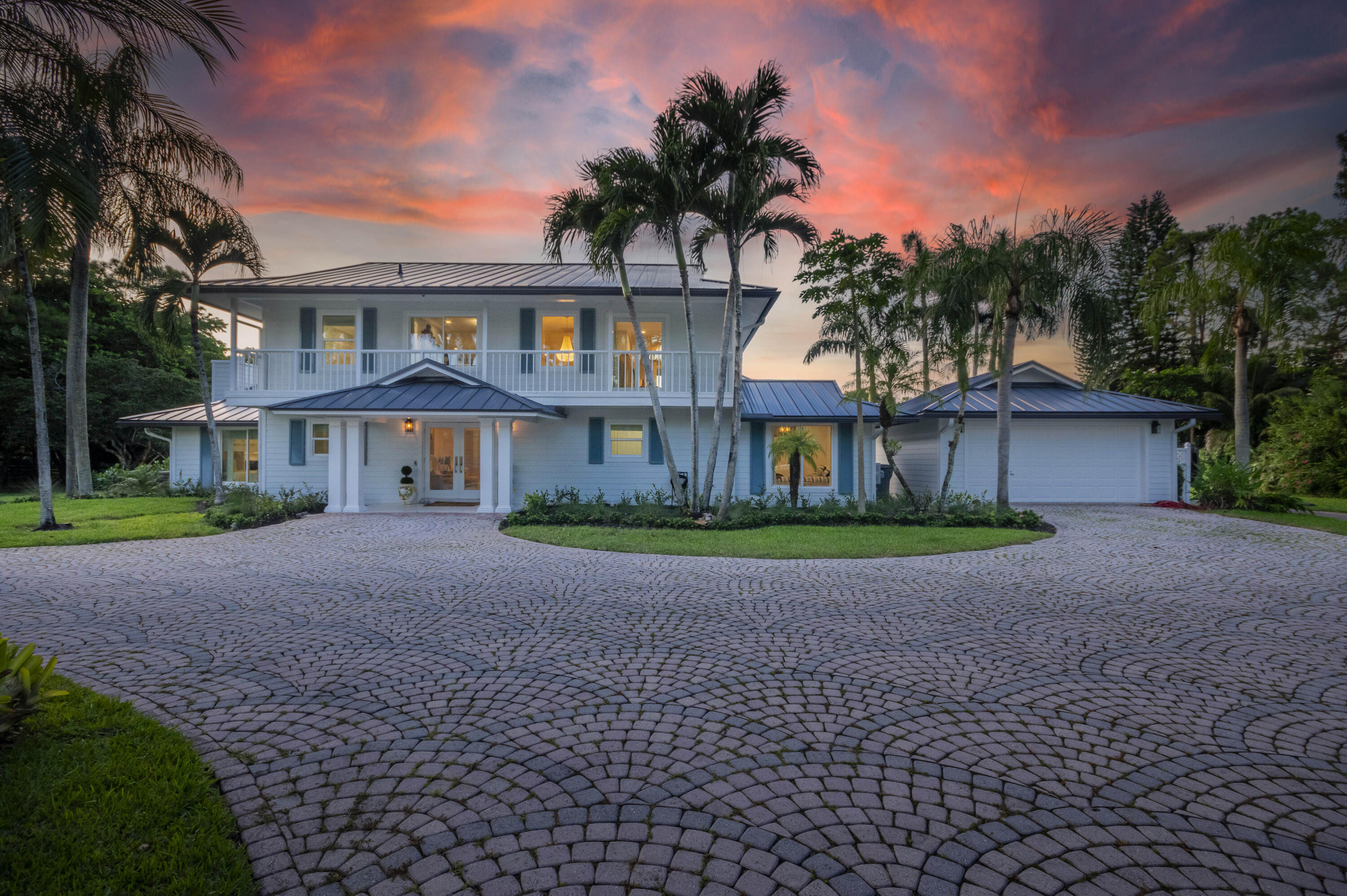 Escape to your private South Florida sanctuary, an equestrian-ready modern French Country estate that redefines refined living on over five acres of lush, manicured land. Thoughtfully redesigned from top to bottom, this exceptional property blends timeless European charm with the ease and sophistication of contemporary luxury living, offering a rare combination of tranquility, craftsmanship, and functionality. A long private drive sets the tone as vaulted, skylit ceilings, walls of glass, and wide-plank European oak flooring flood the interiors with natural light and understated elegance. The heart of the home is the show-stopping chef's kitchen, anchored by dual oversized islands, quartz countertops, and ceiling-height custom cabinetry. A statement wood hood crowns the professional LaCanche range, complemented by top-tier appliances including a Miele coffee system and wine cooler, perfectly designed for both daily living and elevated entertaining. The serene primary suite is a true retreat, offering dual exposures to the marble pool terrace and grand front approach. Its spa-inspired bath features exquisite marble finishes, a soaking tub, and a custom boutique-style walk-in closet. Outdoors, the estate transforms into an entertainer's paradise with a brand-new saltwater pool, sandblasted marble deck, and covered loggia with a fully equipped summer kitchen featuring Hestan appliances and an Alfa pizza oven, ideal for sunset gatherings and alfresco dining. Equestrians will appreciate the newly completed horse barn featuring four stalls, a dedicated feed room, and tack area, making this property truly move-in ready for horse enthusiasts. Expansive fenced pastures, manicured grounds, and existing coops for fresh eggs complete the refined country lifestyle, while an additional fully insulated, temperature-controlled barn offers endless flexibility as a workshop, collector's garage, or future customization. Modern conveniences abound, including full impact windows and doors, a brand-new metal roof, concrete stucco construction, new septic and water filtration systems, and a whole-house generator for peace of mind. Located in Palm Beach Gardens' sought-after Caloosa community, residents enjoy access to 30 miles of scenic bridle paths, a 32-acre equestrian park with riding arenas, and unmatched privacy, just minutes from world-class golf, luxury shopping, fine dining, private aviation, and top medical facilities. This is a rare opportunity to own a fully turn-key, equestrian-ready estate where timeless design meets modern South Florida living.