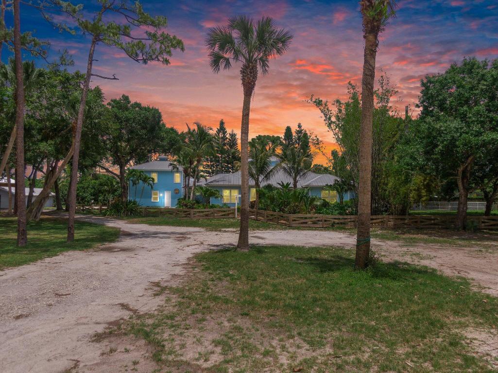 Experience timeless luxury and laid-back elegance on this gated 3-acre equestrian estate in Stuart. Surrounded by a 7-ft privacy wall, this private compound features a beautifully updated 3BR/2BA main residence with a screened in patio, a detached 1BR/1BA guest house, 3-stall barn with tack room, an expansive workshop, and two oversized storage buildings. Enjoy private gated access to the adjacent golf course and peaceful, open grounds perfect for riding or relaxing. Zoned residential/agricultural, this exceptional property offers unmatched versatility, privacy, and charm—a true sanctuary to call home.