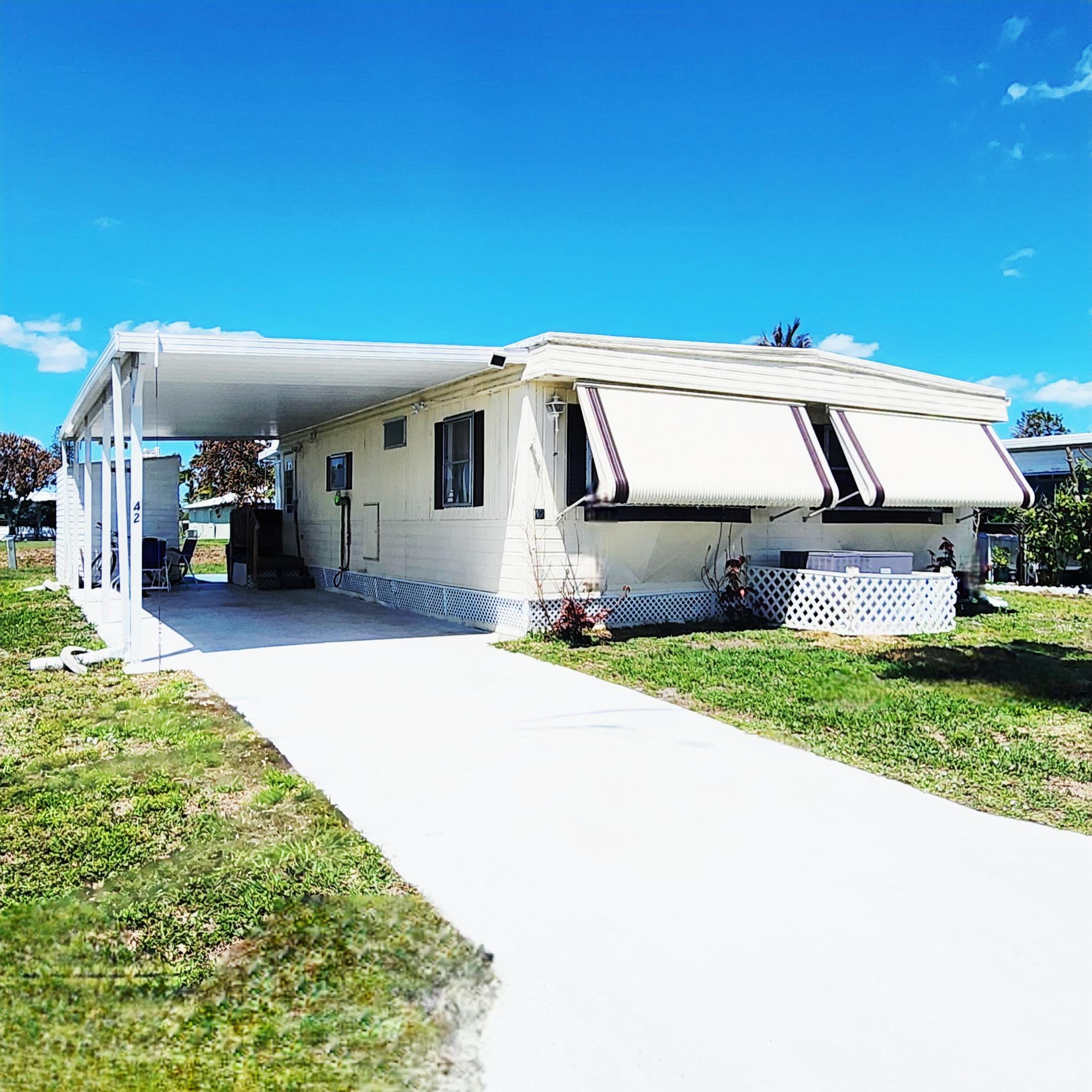 Must see & priced to sell! Beautiful Water Views & Sunsets w/ this charming 2bed/1.5 bathroom. Roof & AC2024 & 2022 Flooring. Step inside & beauty continues w/ spacious kitchen, ample cabinetry, 2025 SS appliances. Complete set Storm shutters included! Master bed. boasts en-suite half bath; while spare bedroom is ideal for guests/home office. Relax & enjoy the views in the enclosed Florida room. A covered carport and storage shed adds extra convenience. Large sized offers space great for pets, gardening, grilling & more! PRIME LOCATION;near beach, grocery, postal, banks, hospital, pharmacy & more! Lot Lease 892.53 incl. trash, lawn, private free golf, heated pool, fitness, pickleball/tennis, shuffleboard,bocce, gym, library, cards,MahJong, workshop, parades, dinners, dances, trips & more!