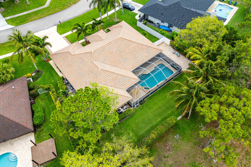 Look no further in this highly sought-after, no-HOA community of Chatsworth Village! This exceptional 5-bedroom, 3-bathroom single-story pool home boasts unique architectural design, soaring cathedral ceilings, and seamless pergo flooring throughout. At the heart of the home is an updated chef's kitchen equipped with granite countertops, a tumbled stone backsplash, premium stainless steel appliances and an extended bi-level island perfect for daily living and entertaining. The highly desirable 3-way split floor plan offers ultimate privacy: The spacious primary suite features, dual sinks, a separate shower, and a relaxing spa tub. Step outside to your private backyard oasis, complete with a deep covered patio, Grecian style pool and cascading waterfall feature. The back yard is fully fenced and has a side gate access to park your  boat. For complete peace of mind, the property comes equipped with accordion storm shutters and a whole-house generator powered by an owned, on-site 750-gallon propane tank—capable of running the entire estate for up to 10 days and a 2016 Barrel Tile roof.  Complete with a central vacuum system and a dedicated interior laundry room with built-ins, Exterior of house was recently painted.  This home is located just minutes from the Winter Equestrian Festival, premier shopping, fine dining, and top-rated schools. Walking path is located right behind the house.