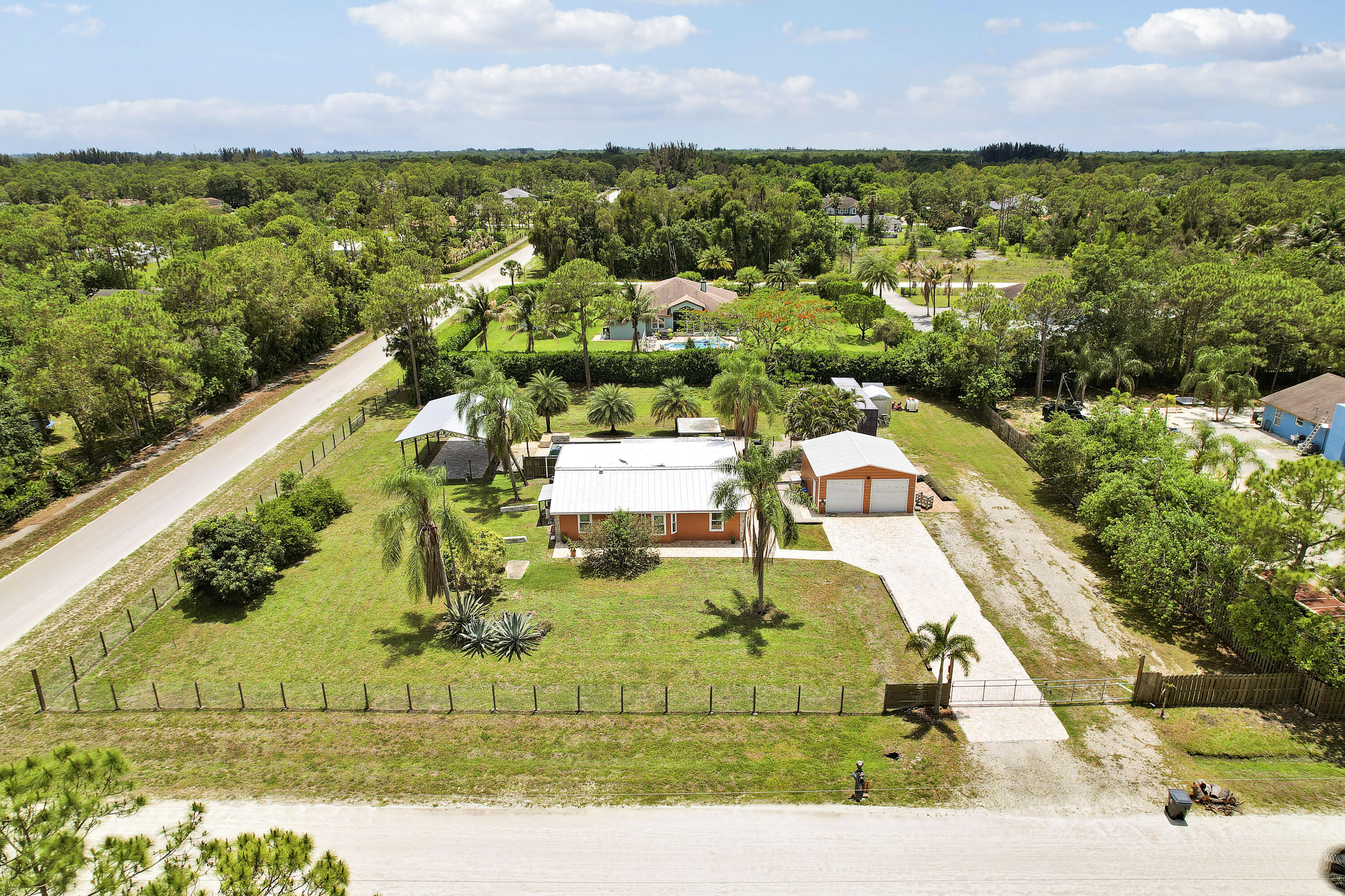 Enjoy peaceful acreage living with room to spread out. Set on an incredible 1.28 acres in Loxahatchee, this 3BR/2BA home offers the space and outdoor setup everyone is looking for. The backyard steals the show with a heated pool and spa redone in 2022, screened patio, outdoor kitchen with a pizza oven, Green Egg, and outdoor shower, expansive yard space, covered RV port, RV/boat parking, detached 2-car garage, generator, and storage container. Inside features an open floor plan, premium waterproof laminate flooring, updated bathrooms with walk-in showers, walk-in closets with built-ins, black Whirlpool appliances (2020), impact windows, and a 2021 metal roof. Chlorine pool system with saltwater option available.