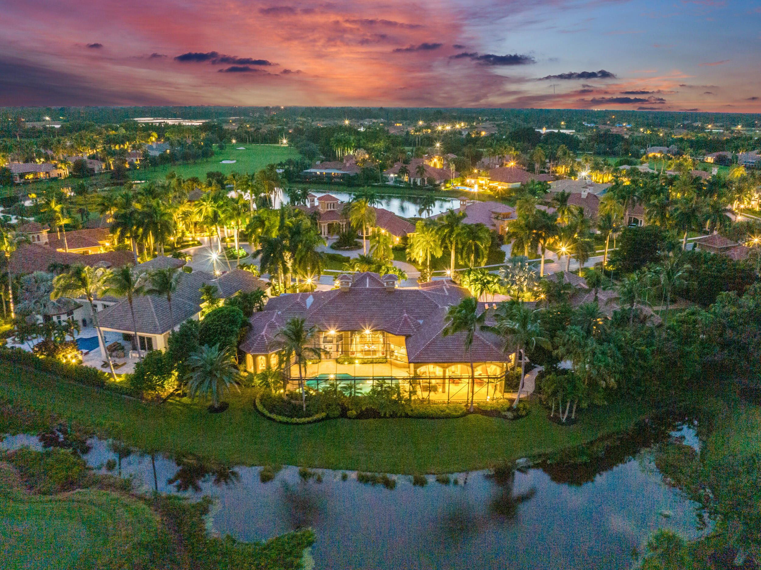 Situated on THE LARGEST LOT in Ibis's prestigious Eagle's Isle neighborhood, this masterfully built and beautifully appointed custom Cribb-build estate boasts TWO SEPARATE HOMES connected by a dramatic walkway. With 6BR/6.5BA+LIBRARY/ 5-CAR GARAGE including an epic GUEST HOUSE, featuring 500 sweeping feet of prime golf and water views east, this estate provides panoramic views of the 12th hole of Nicklaus' redesigned Legend Course. As you approach the residence, you'll first notice the 1700 SF guest house, architecturally designed to complement the main home. Both residences feature BRAND NEW ROOFS and gutters installed in 2022 and IMPACT GLASS throughout. PREMIER GOLF MEMBERSHIP available on Day 1 with the purchase of this property. The circular Chicago Brick driveway and wood trimmed port o cochere welcome you to this one-of-a-kind estate. Everywhere you look, you will appreciate the fine materials and quality craftsmanship.The interior impresses from the moment you enter with its soaring box-beam ceilings, timeless marble flooring laid in a French Pattern, dramatic inlays, columns, moldings, custom millwork, and architectural and designer enhancements that grace every single room. The owners spared no expense in creating a luxuriously appointed estate on an incomparable lot. Professionally decorated in an opulent Mediterranean style with Asian influences, the estate's architectural details provide a palette of rich jewel tones which enhance the natural tones of the woods used throughout. An oversized kitchen opens graciously to the Family Room and features custom wood cabinetry, a gourmet stainless appliance package (SubZero and Dacor), accentuated by the timeless and substantial sueded Double Ogee Edge marble countertops and coordinating backsplash. The 19'x43' owner's suite boasts large walk-in closets and a versatile space designed as an exercise room, however it could easily be reimagined as an art studio, massage room, or even another closet. The very Ralph Lauren library is adorned with rich inlayed hardwood floors, custom wood-paneled walls and a handsome bar creating a sophisticated and warm ambiance. The large, screened pool and spa area has fabulous covered space for outdoor entertaining and relaxation. Bamboo-accented ceilings and outdoor kitchen, stacked rock waterfalls, and a fountain along the walk to the guest house give the space a tropical, zen-like ambiance designed to inspire comfort and relaxation. Large windows on both sides of the dramatic connecting hallway provide views of the large, private property. The guest house has a spacious great room with soaring ceilings and some major wow-factor provided by the custom, multi-tiered wood-trimmed ceiling. Along with a kitchenette, large screened in porch, and spacious bedroom and bathroom suite, the guest house also features a 2-car garage. The bedrooms in the main house are also oversized, large enough to house two beds in each room. All guest suites are beautifully appointed and ready for guests on Day 1.