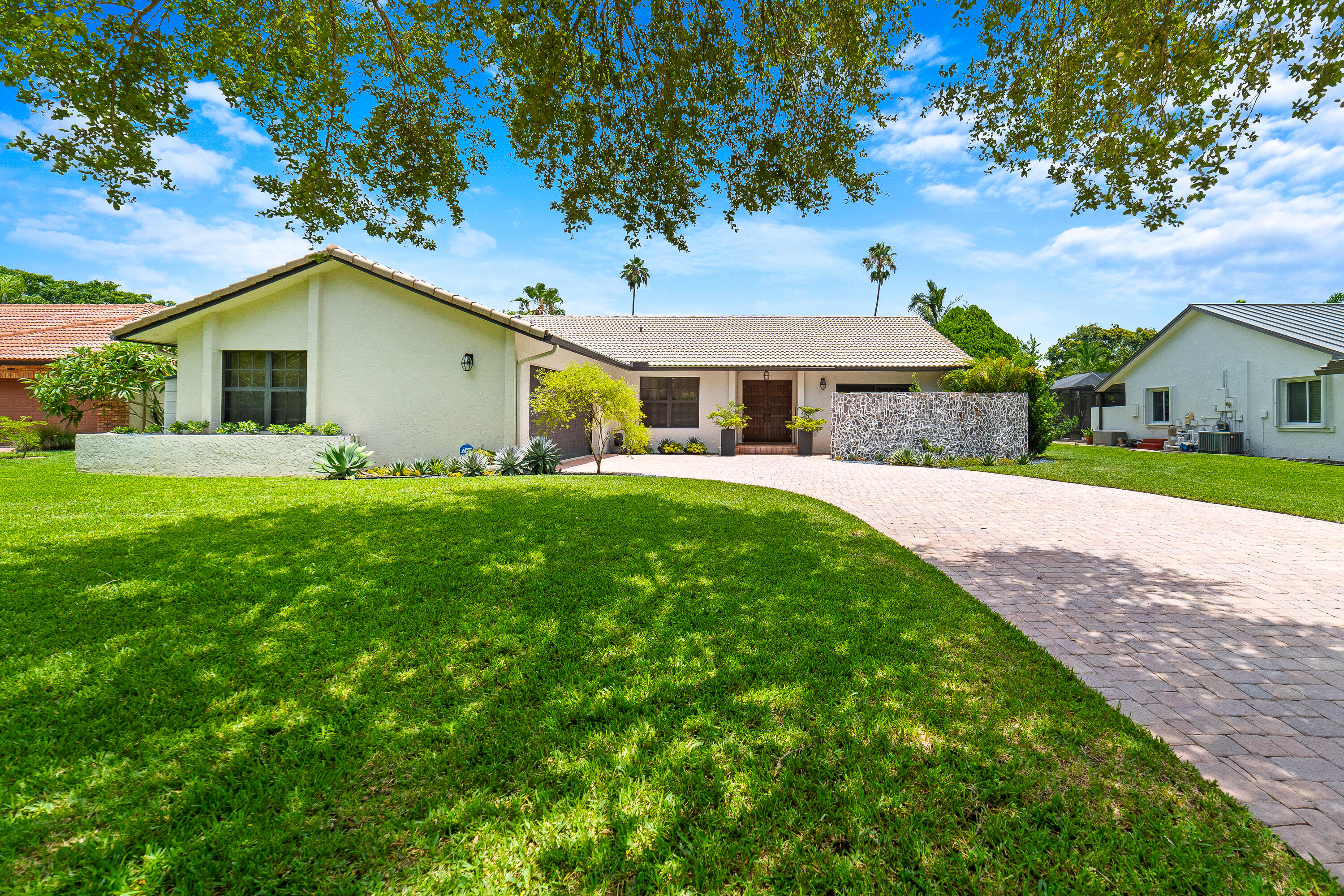 Thoughtfully renovated, this contemporary home sits on a quiet cul-de-sac in the desirable Shadow Wood neighborhood, with no HOA and a well-maintained neighborhood park directly across the street. Excellent curb appeal, a long driveway, and a two-car garage welcome you home. Inside, the open layout shines with a remodeled living and dining area completed in 2023, featuring recessed lighting, updated fixtures, and a custom electric fireplace with built-in shelving. The fully remodeled kitchen with custom cabinetry and the updated bathrooms complement the home's modern design. Major updates include a variable-speed A/C, newer water heater, kitchen appliances, and hurricane-impact windows and doors. Abundant built-in storage adds everyday functionality.  The private backyard backs to a tranquil canal lined with mature trees, creating a peaceful setting to relax or entertain by the pool.