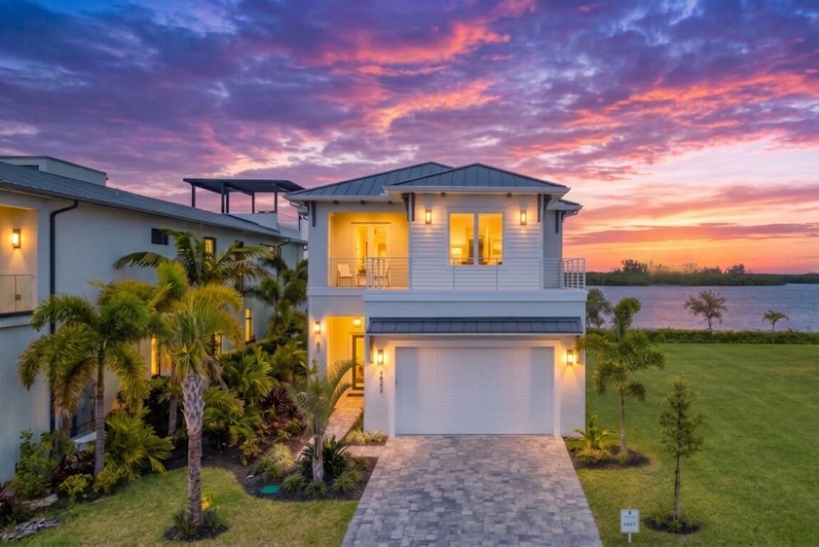 Welcome to the exquisite coastal-style home situated in the highly sought-after Laguna Village directly on the Intracoastal/Indian River within prestigious Grand Harbor. This brand new construction offers the ultimate in luxury and comfort, with direct riverfront views and an impressive 4 bedrooms, 4 full bathrooms, and 2 half bathrooms. The al fresco riverfront kitchen is perfect for entertaining guests and enjoying outdoor meals while taking in the breathtaking river views. Sip your coffee & watch the sunrise from your riverfront lanai complete with summer kitchen, fire pit and fire features & putting green.   With over 3,786 square feet of air-conditioned living space and a total of over 5,000 square feet, this 2-story home is designed to exceed your expectations.  Built with the utmost attention to detail, this home features 12 foot ceilings in the living spaces and 10' ceilings upstairs. The open floorplan kitchen features custom cabinetry and a spacious island. The private dining room is complete with a walk in wine vault with cold storage for 150 bottles and dry storage for 130 more.  The primary suite is complete with a spacious bath, huge shower and soaking tub with spectacular river views. The custom walk in closet has a large island. Its best feature is a large covered patio with river views for miles. The concrete block construction, a durable metal roof, impact glass windows, and icynene insulation provide optimal energy efficiency and safety. For added convenience, an elevator is included, providing easy access to all levels of the home. The custom garage by Obsessed Garage provides ample space for your vehicles and storage needs.  This is coastal living at its finest, where every detail has been carefully considered to create a truly exceptional living experience. Indulge in the resort-style amenities that Laguna Village at Grand Harbor has to offer, including 2 world class golf courses, safe harbor marina, tennis, pickle ball, luxury clubhouse w/ dining, oceanfront beach club and the new state of the art 15,000 sq ft Cove wellness and fitness center. Immerse yourself in the natural beauty of the surrounding landscape, with lush greenery and serene waterways at your doorstep.