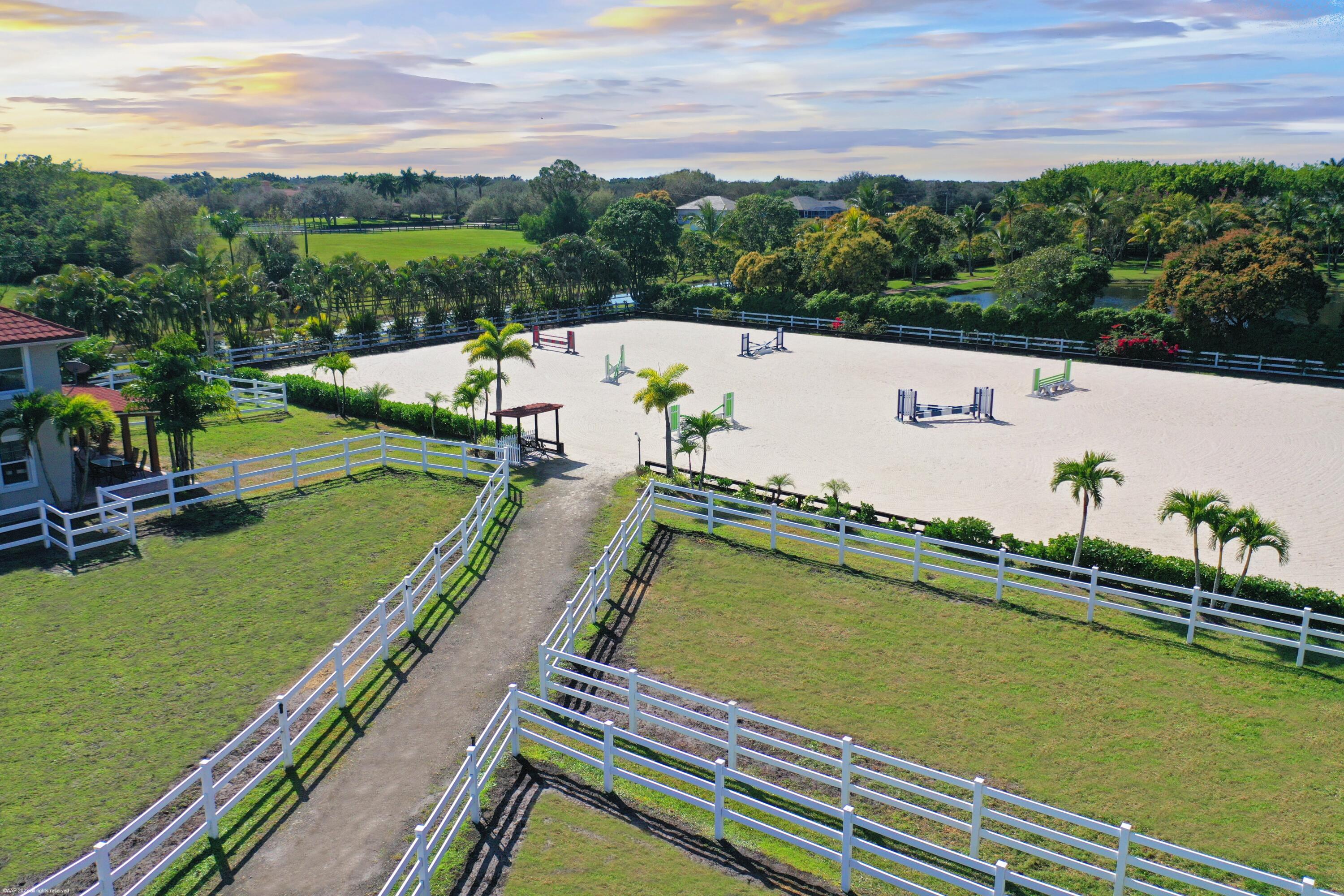 Situated on 5 acres within the gates of Palm Beach Point, this private end of street location with stunning landscape offers a rare combination of residential comfort & professional training facilities. This 4Br estate homes with an office features spacious entertaining areas, a detached cabana studio with full bath & 3-car garage. The income producing equestrian amenities include a 13-stall stable built in 2014 with 2 wash racks, 9 paddocks, and a 125' x 200' riding arena. Three apartments, totaling 7 bedrooms, provide next level accommodations for staff. Additional features include: new impact windows & doors, 50 year metal roof, covered treadmill area, RO water treatment system and ringside covered-patio viewing area. This meticulously maintained home is a great canvas to make your own PRIMARY RESIDENCE:
4 Bedrooms in main residence, plus a detached poolside 330 sq. ft. studio apt. with full bath.
Cabana bathroom with shower
2024 All new impact windows & doors
New Roof in 2006 - 50-year metal with tile look (house, barn & apartments). 
Mahogany built-ins 
Central vacuum
3 Car garage with mini-split A/C
4 A/C units/zones: 1) primary bedroom, 2) 3 guest rooms, 3)  Kitchen & family 4) office, dining room, formal living.

KITCHEN:
Mahogany cabinets
Glass cooktop
Prep sink
Wall oven
Microwave/convection combo
Kitchen Aid warming drawer
Two dishwashers 
Trash Compactor
Walk-in Pantry

FAMILY ROOM:
Cedar built-in
Wet-bar with sink, wine cooler & ice maker

ATTACHED STUDIO:
Kitchenette with new cooktop
1 full bathroom with tub
New vinyl flooring

Generator hook up: runs the essentials: 1 A/C and Refrigerator.

POOL & PATIO:
Waterfall, chlorine, plumbed for heater.
Propane tank for gas pool heater
BBQ & bar area: with exhaust hood & sink
New pool pump 2021
Separate pump for front entry fountain

The Stables:
Built in 2014 
12 - 12' X 12 Stalls
1 - 15' X 12' Stall
Water to each stall 
Hurricane Roll Down Doors
Laundry, Feed, Tack & Storage Rooms
1/2 Bath in stable
Covered Treadmill Area

3 APARTMENTS:
1 Studio Apartment or Lounge - Ground Level - 559 sq. ft.
4 Bedrooms / 3 Bathrooms - 1,426 sq. ft.
2 Bedroom with Jack & Jill bath - 700 sq. ft.
Total square feet of barn apartments: 2,685 sq. ft.

Irrigation source is from the canal with a separate arena pump from canal.
Kinetico RO Water Treatment System: supplies the house & barn -  replaced approx. 2017/2018.