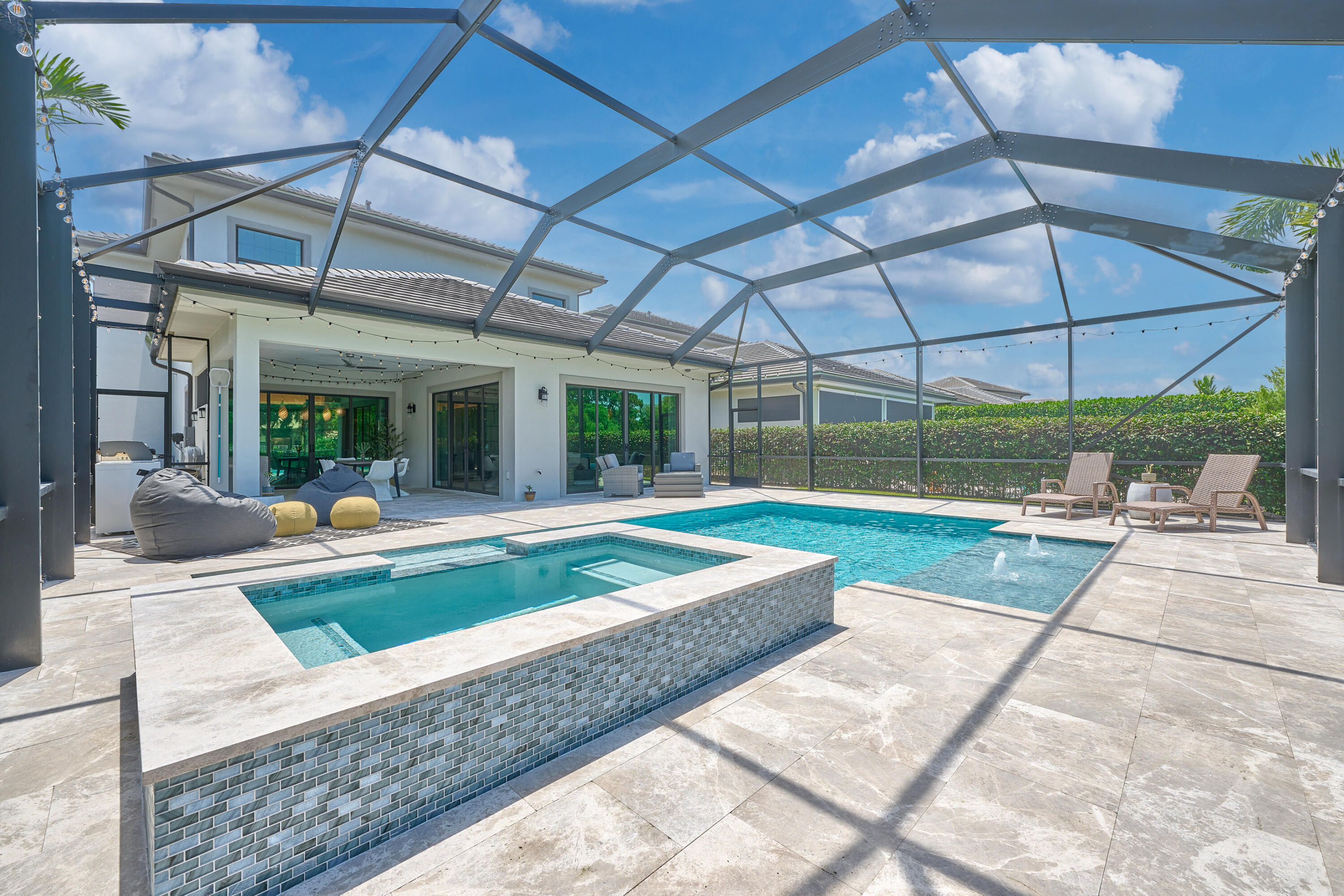An exceptional opportunity inside the exclusive, 24-hour guard-gated enclave of Banyan Cay. Built in 2021 and extensively enhanced with designer upgrades throughout, this contemporary waterfront residence offers 3 bedrooms, 3.5 bathrooms, over 3,200 square feet of impeccably designed living space, and a private resort-style backyard featuring a newly renovated pool and hot tub. Set perfectly within the community to capture peaceful, quiet surroundings, the home features an expansive two-story floor plan spanning over 3,200 square feet of impeccably designed interior space, with high ceilings, glass sliders, custom lighting, designer paint selections, Sonos in-ceiling speakers, art display niches with built-in lighting, and thoughtfully curated finishes that create a warm yet sophisticated  atmosphere. Custom barn doors, an expanded primary closet system, new designer flooring on the staircase and second floor, and an epoxy-floor garage with overhead storage further enhance the home's exceptional functionality and style. The dramatic Great Room flows seamlessly into a stunning chef's kitchen with a massive entertaining island and expansive sliding glass doors that blur the line between indoor and outdoor living.  The backyard has been completely transformed into a private resort retreat. A major 2026 renovation includes an expanded marble pool deck, an extended sun shelf with bubblers, new pool lighting, designer tile, and a state-of-the-art smart pool control system accessible from your mobile device. The covered lanai is complemented by a custom outdoor kitchen with a porcelain backsplash, ambient string lighting, and an expansive screened enclosure designed for year-round entertaining. Professionally designed landscaping creates exceptional curb appeal and privacy with lush tropical plantings, jasmine-covered fencing, landscape lighting, elegant paver walkways, and an inviting front patio seating area. Every detail has been carefully considered to maximize beauty, privacy, and low-maintenance living. The spacious floor plan includes a luxurious primary suite retreat and two elegant en-suite guest accommodations, offering flexibility for a home office, fitness room, or private guest quarters. Located just steps from The BELGROVE (a Marriott Autograph Collection Resort & Spa), the reimagined DUTCHMAN'S PIPE Country Club (a Jack Nicklaus Signature golf course), and a premier fitness and racquet center featuring tennis, pickleball, and padel, with flexible membership options and exclusive offerings for Banyan Cay residents. Just minutes from Downtown West Palm Beach, Palm Beach Island, Worth Avenue, world-class dining, shopping, cultural attractions, and Palm Beach International Airport, this turnkey residence offers the very best of Palm Beach luxury living.