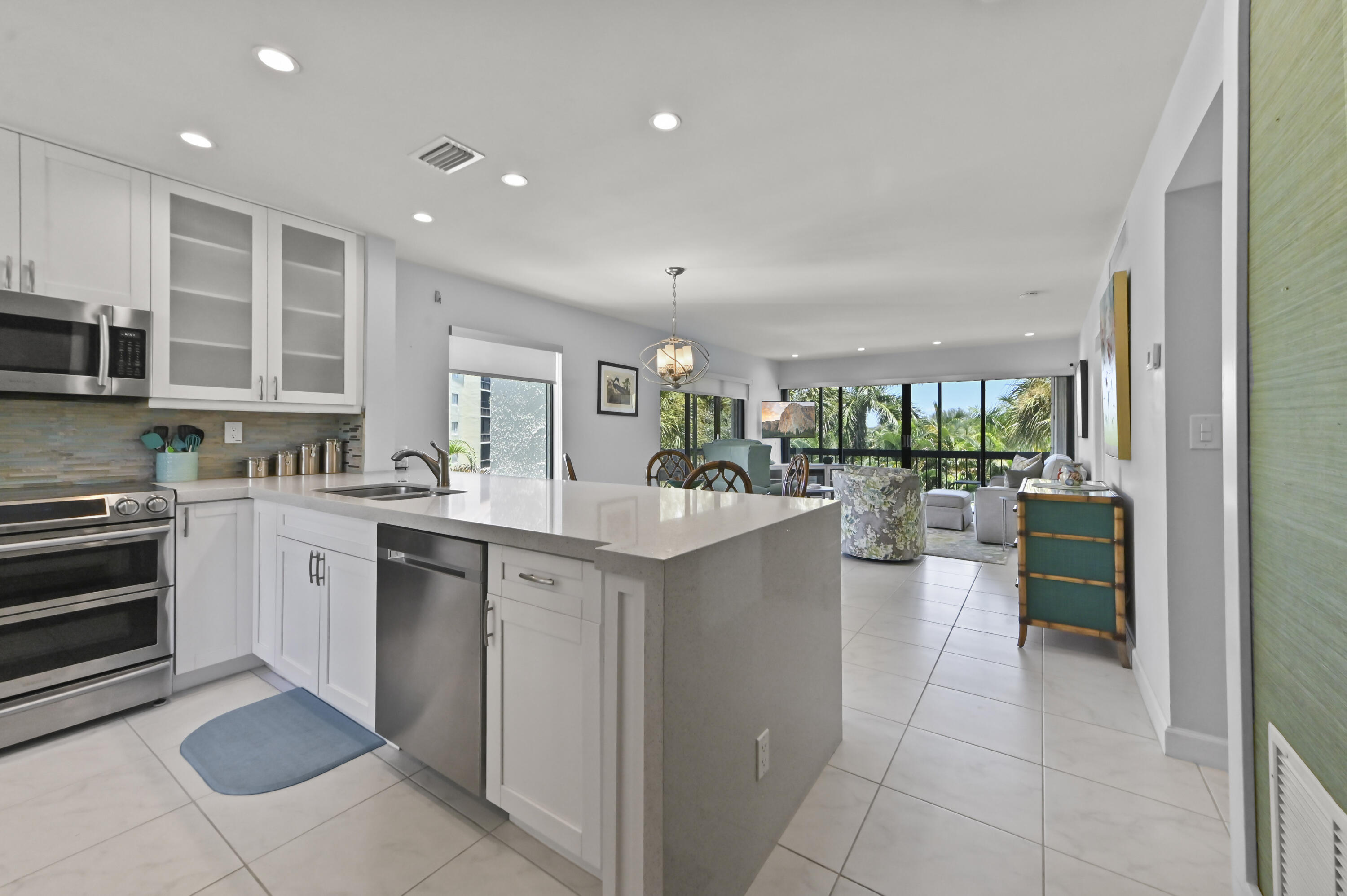 Step into this beautiful top-floor corner condo, where modern designer finishes, abundant natural light, and a thoughtful layout create an inviting place to call home. Fully renovated in 2018, the cozy kitchen features sleek cabinetry, quality appliances, generous storage, and contemporary details that flow seamlessly into the spacious living and dining areas. Ceramic tile flooring, built-in features, roller shades, 2020 AC and a tankless water heater add comfort and convenience throughout. The split-bedroom floor plan offers privacy, with two generously sized bedrooms and two beautiful bathrooms. The primary suite includes a walk-in closet and a well-appointed private bath, while in-unit laundry makes everyday living effortless. Accordion hurricane shutters provide added peace of mind, and the home's corner location allows natural light to fill the interior from multiple directions.  Relax and unwind on the screened wraparound balcony while enjoying peaceful views of the community pool, landscaped grounds, and colorful Florida sunsets. Located within the gated Lands of the President community, residents enjoy access to a swimming pool, clubhouse, elevator, sidewalks, storage, and attended security. This move-in-ready residence offers the perfect combination of stylish interior living, relaxing outdoor space, and a convenient West Palm Beach location.