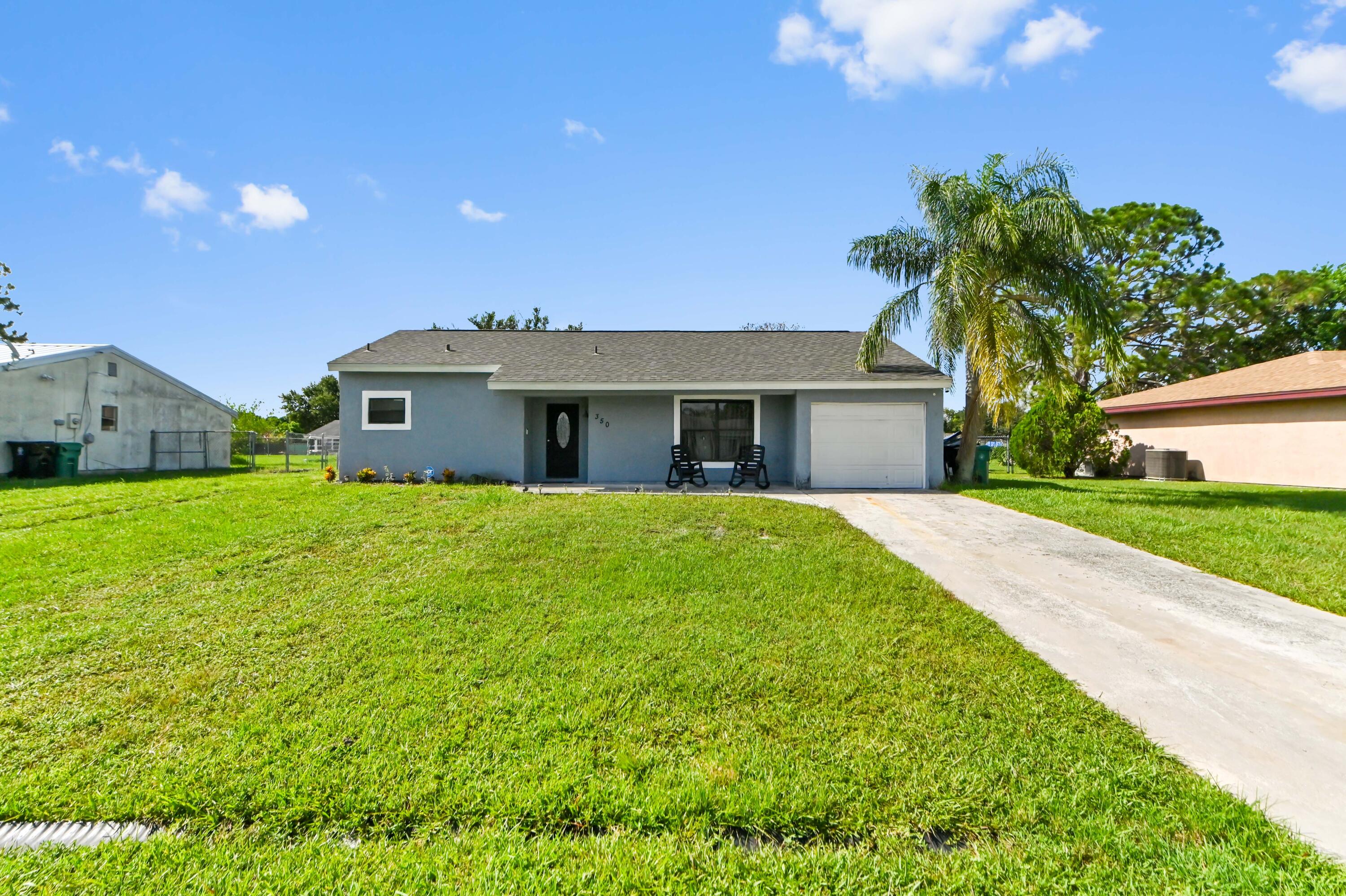 Welcome to 350 SW Homeland Road, a charming three-bedroom, two-bathroom home offering 1,421 square feet of comfortable, single-level living in Port St. Lucie. The inviting floor plan features a spacious main living area, a dedicated dining space and a practical kitchen equipped with ample cabinetry and a full complement of appliances. All three bedrooms are conveniently located on the main level, while a walk-in closet and versatile bonus area provide additional flexibility for a home office, hobby room or guest space. Enjoy added peace of mind with several important improvement already completed, including a roof replaced in 2023, The home also offers indoor laundry, central heating and cooling, and the convenience of public water and sewer service, creating a comfortable and functional setting for everyday living.  Step outside to a generously sized, fully fenced backyard with plenty of room for outdoor gatherings, gardening, pets or future enhancements. Set on approximately a quarter-acre lot, the property offers desirable outdoor space while remaining close to shopping, restaurants, medical offices and local schools. With its flexible layout, valuable improvements and convenient location, this home is ready for its next chapter.