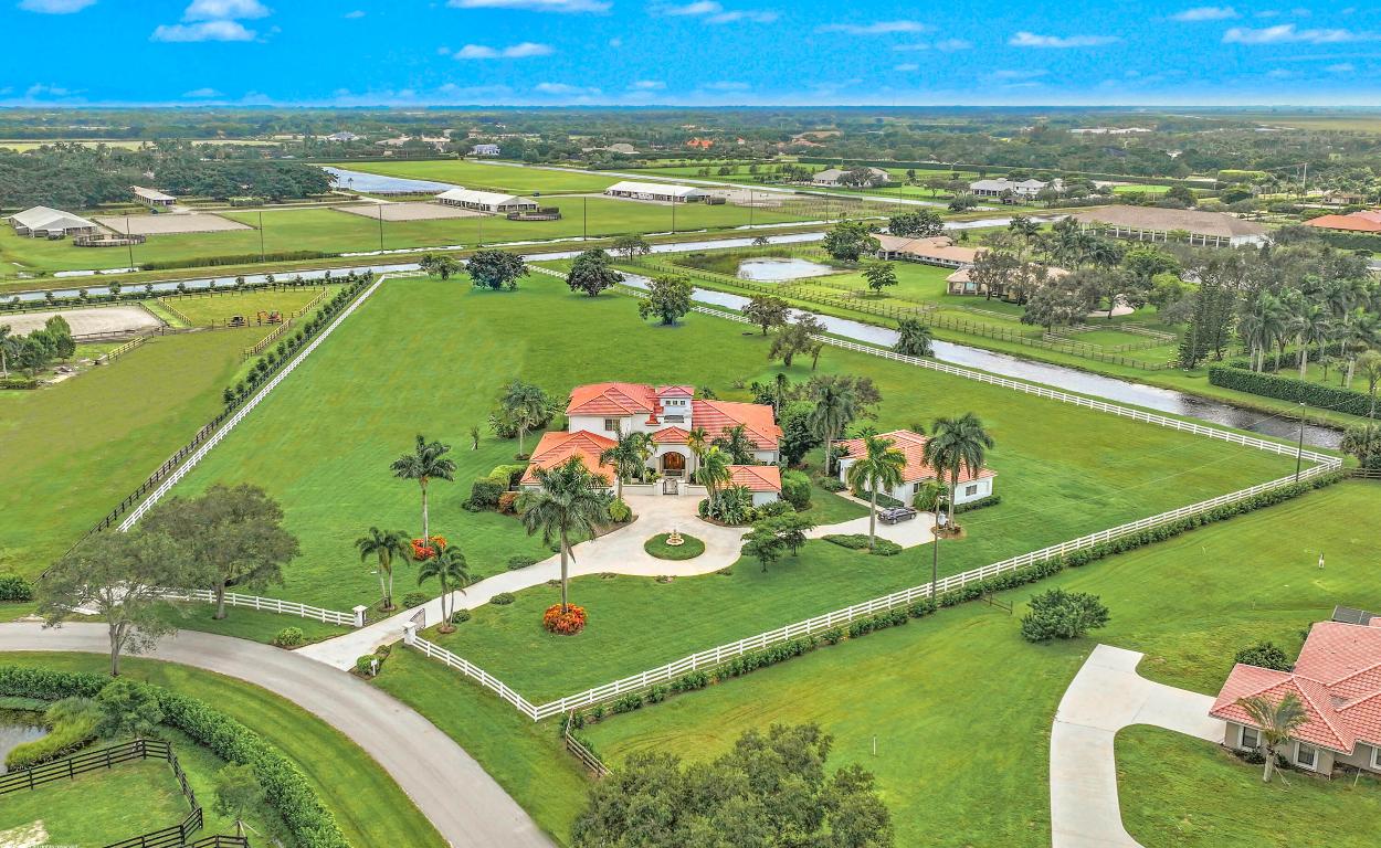 Stunning estate home with guest house situated on 6.68 acres, one of Palm Beach Point's largest lots & hackable to the WEF Showgrounds expansion. This meticulously maintained property provides the perfect canvas to style the residence your way and custom build the equestrian amenities. The main residence boasts 4Br's plus an office, 14' ceilings, home-theater, personal gym and loft area. The Kitchen features a center-island, gas cooking & double ovens. The home has beautiful natural light, mahogany wood floors, an expansive pool & patio w/built-in BBQ area, gated entry drive & 4 car garage. The private detached 2Br guesthouse features a den & screened patio, perfect for staff or the in-laws. Don't miss out on this great opportunity to be on an oversized lot in a prime location! GENERAL INFORMATION:
Perimeter fencing, entrance gate installed in 2020
Termite Sentricon system installed and under contract
New septic pumps and alarm 2024
Pergola and outdoor kitchen installed 2023
7.5 inch hardwood plank flooring in primary bedroom,
stairs and upstairs library
Booster pump on water system
Security system
Whole house sound system

MAIN HOUSE:
New tile roof in 2018 and Guest house
Exterior repainted in 2022
Heat pump/air conditioners all replaced in 
last 8 years
Hot water heaters all replaced in last 6 years
Pool deck and pool resurfaced 2017
New dishwasher and microwave in kitchen

GUEST HOUSE:
New tile roof in 2018
Exterior repainted in 2022
New carpet in guest house 2025
All kitchen appliances replaced in 2023
Hot water heater replaced in 2023
New A/C installed in 2022