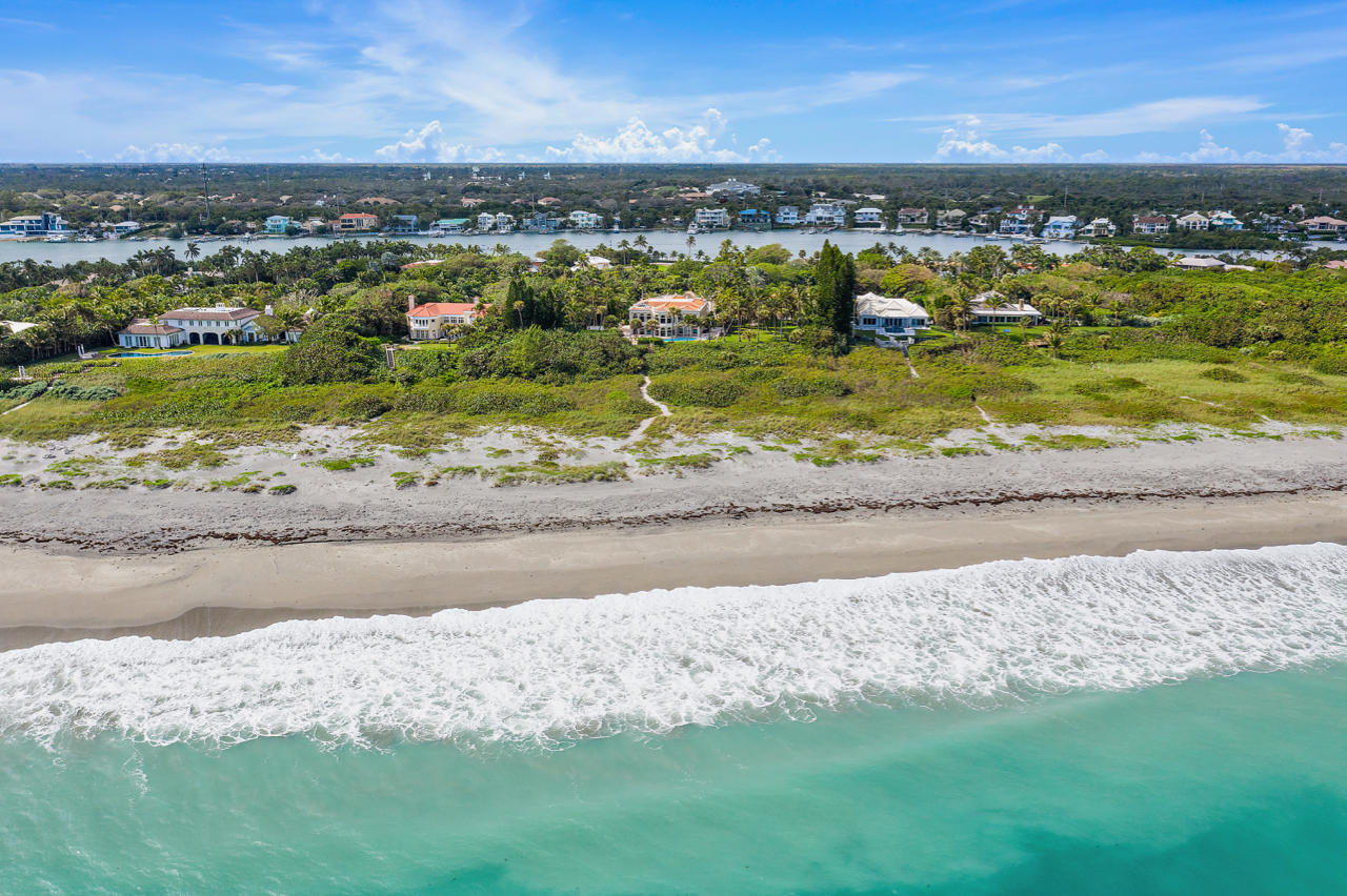 Perched on over 5 acres of prime oceanfront land on Jupiter Island and hidden behind a veil of towering palm trees and perfectly manicured lawns, lies a marriage of five meticulously crafted buildings. The natural elevation of this grand property allows for unobstructed views of 262 feet of private, pristine beach. Entering the two-story iron gates, one comes upon the majestic main Villa, notably inspired by 12th century Italian design. Guests are invited to find solitude in one of three enchanting Tower Apartments, or in the stately Guesthouse by the beach. Follow a flower lined descending path featuring a cascading fountain and mosaic pool, and you'll find a wellness oasis complete with steam room, sauna, and Turkish bath. Dozens more water features and statues are strategically placed around the planned grounds, where entertaining takes center stage and continues onto the beach. A separate service entrance leads to the staff quarters of seven bedrooms with a six-car garage and motor court. Enjoy this crown jewel of Jupiter Island, or build a new compound on one of the largest oceanfront settings in South Florida, with a buildable area of over 25,000sf.