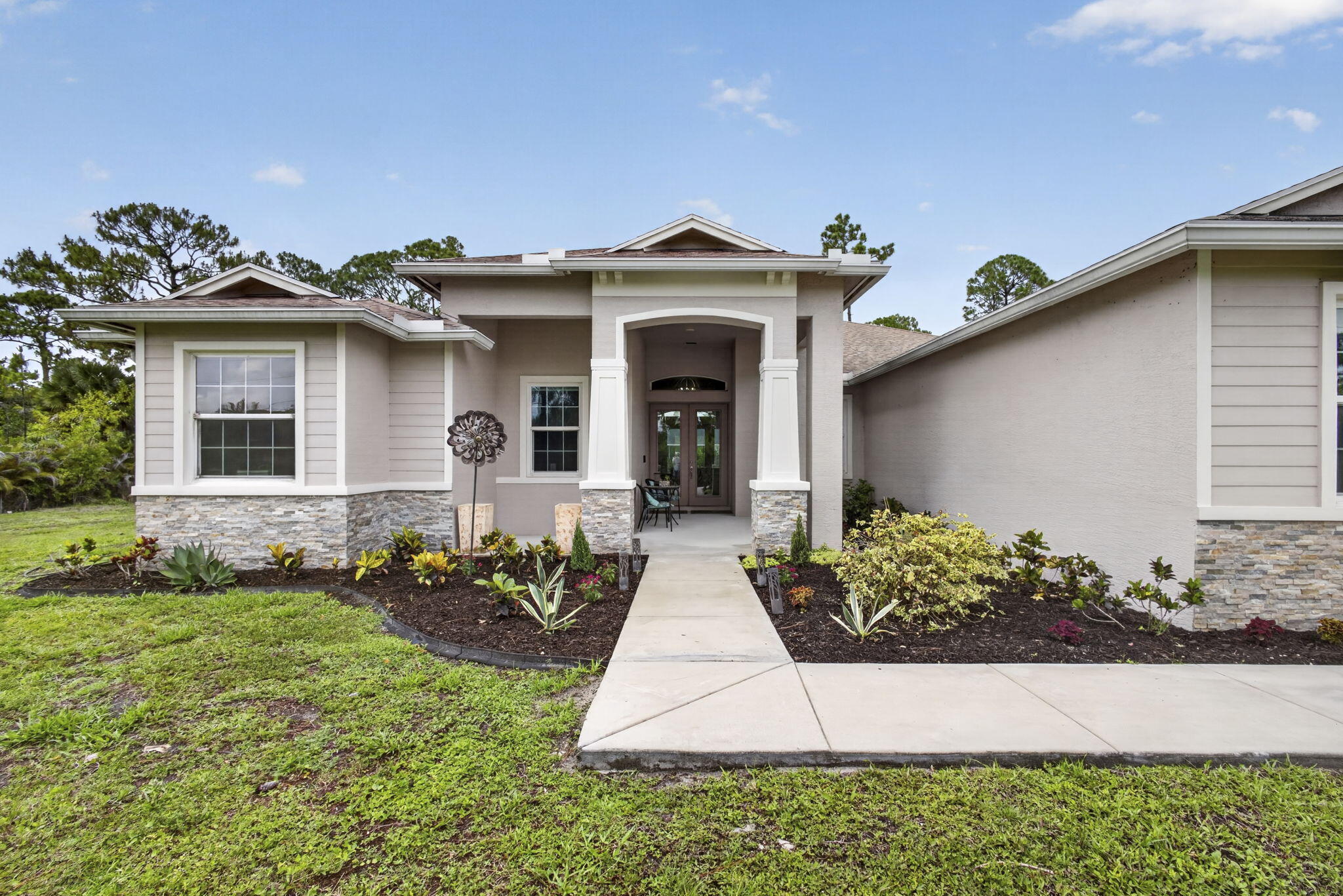 Welcome to this exceptional 2022 custom-built Synergy Home situated on a rare 1.14-acre lot in Loxahatchee offering BOTH paved road access and city water — an incredibly hard-to-find combination. This move-in ready CBS construction home features 4 bedrooms, 3 bathrooms, plus a den, with luxury finishes and thoughtful upgrades throughout. Step inside to soaring ceilings with custom wood beam accents and an expansive open-concept floor plan designed for both everyday living and entertaining. The chef's kitchen is the centerpiece of the home, showcasing a gas Viking range, oversized walk-in pantry, custom cabinetry, luxury chandeliers, and seamless flow into the living and dining spaces. Wood-look tile runs throughout the entire home,  while spacious bedrooms feature 10-foot ceilings for an airy and upscale feel. The private backyard is framed with mature clusia hedging and offers gas stub-outs ready for a future outdoor kitchen. Additional highlights include impact glass windows and doors, gas water heater, large laundry room with extra cabinetry, sprinkler system, full concrete driveway, Solar powered electric, and a spacious 3-car side-entry garage. Enjoy the freedom of NO HOA with plenty of room for animals, boats, RVs, and more. Conveniently located near shopping and dining in Westlake and Avenir, with easy access to major roadways, just 15 minutes to the Turnpike and I-95. Located in an A-rated school district. A rare opportunity to own a newer construction luxury acreage home with modern infrastructure, premium upgrades, and unmatched convenience.