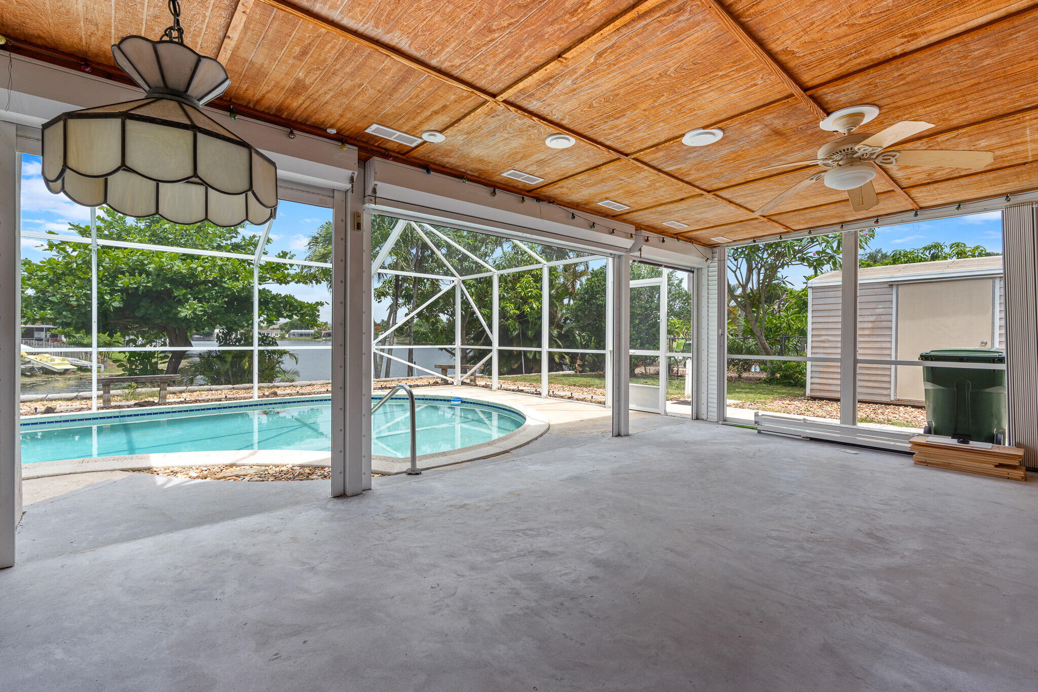 The view, the view, the view! From your pool overlooking the lake to the spacious screened-in patio, the outdoor living space here is truly exceptional. Offering over 1,700 square feet, this freshly painted 3-bedroom, 2-bath home sits on a large lot and features tile flooring throughout. The split-bedroom floor plan provides added privacy, with the primary suite separated from the additional bedrooms. An extra room adds incredible flexibility and can easily function as a home office, media room, gym, playroom, or additional lounge space. The spacious laundry room even includes a fun fridge, while two outdoor sheds provide plenty of extra storage for holiday decorations, lawn equipment, and more.  Bright, spacious, and full of charm, this home combines comfortable living with beautiful water views — ready to welcome its next owners to enjoy everything it has to offer.  Please note, some of the images in this listing have been virtually staged