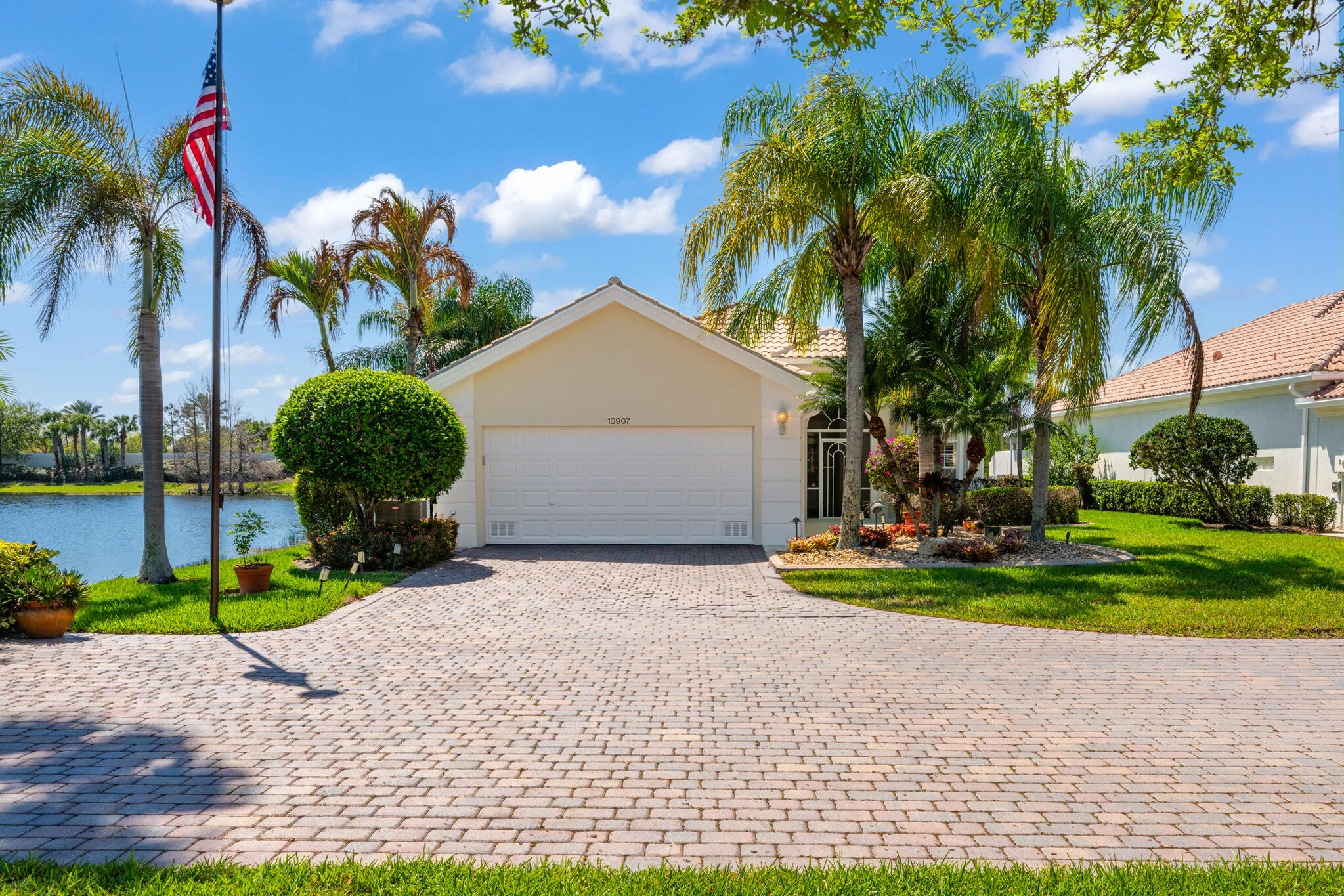 Located in a highly desirable Tradition community, this original owner home sits on a premium corner lot surrounded by water on two sides. A standout feature is the expansive L-shaped driveway, providing ample parking for all your guests. Step inside through the screened entryway and you'll immediately notice the upgraded tile flooring in the living room, kitchen, and den. The glass sliders leading to the pool feature original etched glass artwork that add a unique touch, and the den/study features custom plantation shutters. The kitchen has been updated with stone counters and convenient drawers. The spacious living areas flow seamlessly to the outdoor oasis, where you'll find a heated, screened-in pool and a freshly painted pool deck, perfect for relaxing while enjoying the stunning  water views in all directions!  The owner's suite offers a true retreat with fully remodeled his-and-hers bathrooms, featuring new cabinetry, tile, and etched shower glass. There is ample closet space for all your stuff!  Major system updates include a brand-new 2026 air conditioning system and this home's exterior has been freshly painted in February 2026. The garage has been upgraded with a custom floor and an EV charging station. The enhanced landscaping makes this home stand out in this gated neighborhood within walking distance to shopping and dining in Tradition square! HOA amenities include cable, internet, alarm, lawn care, exterior painting, 24 hour manned gate, clubhouse with social activities, gym, pickleball, tennis, 2 heated pools.