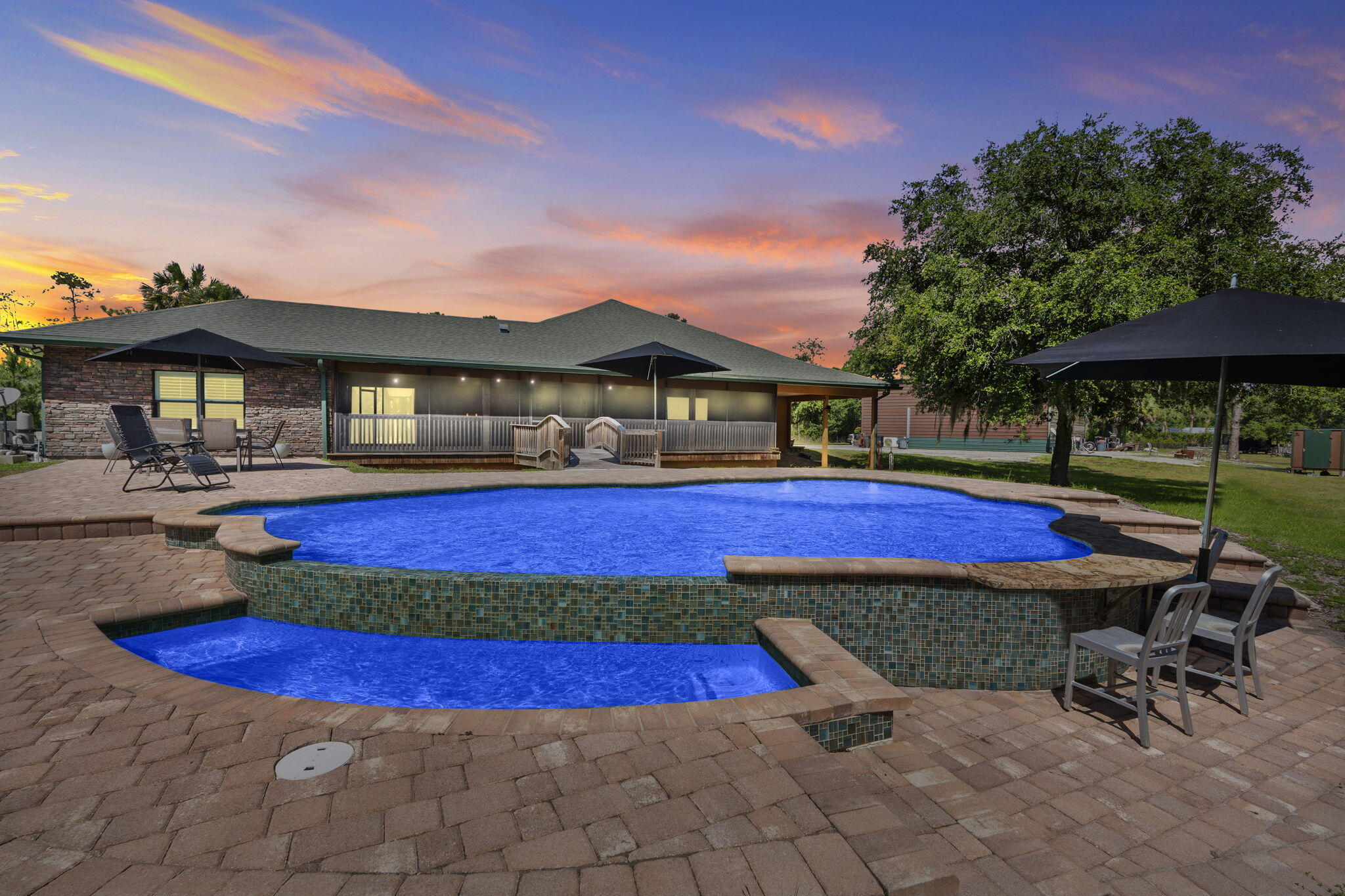 Nestled within Indian Hammock Hunt & Riding Club, custom CBS estate blends rustic charm with luxury living. Log cabin cedar siding, 3 bedrooms, 3 baths, a private guest suite, expansive wraparound porch. Quality construction w/complete impact glass, spray foam insulation, stucco soffits, a tankless water heater, whole-home generator w/ a 1,000-gallon propane tank and over 13 slabs of custom granite. Enjoy a spacious laundry room with a 2nd refrigerator, over 1,600 sq. ft. of screened porches, and a resort-style pool with waterfall, swim-up bar, outdoor kitchen, Jandy sys. fully fenced w/ electric gate includes a 60x40 garage/workshop with a 12x20 office. Community amenities offer a private airstrip, hunting preserve, equestrian trails, fitness center, pool and clubhouse dining.