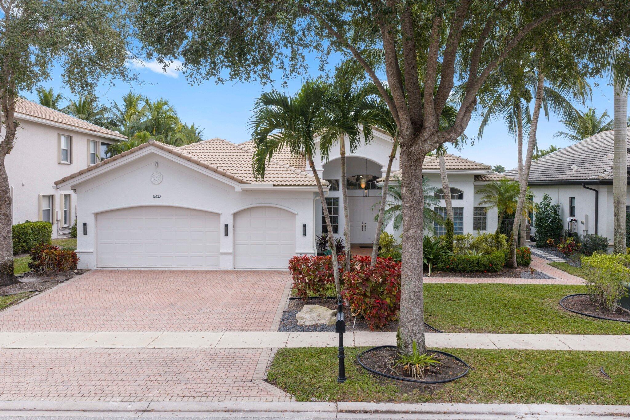 Welcome to 10812 Castle Oak Drive in Boynton Beach, Florida, a beautifully upgraded Indigo model offering 5 bedrooms, 3 bathrooms, and a 3-car garage, with 2,945 square feet under air and 3,859 total square feet. Situated on a rare .23-acre wide-view lakefront lot, this home features an east-facing rear exposure, providing stunning sunrise views along with cooler afternoons and evenings enjoyed from the expansive rear patio. Outdoor living is elevated with a 30' x 15' heated saltwater pool featuring elegant waterfalls, an auto overflow drain system, and newer pool equipment including a chlorine generator and variable-speed pump and filter. The patio is further enhanced by new outdoor fans and a motorized 28' x 8' retractable awning, creating a comfortable and shaded retreat. A lake-water-fed irrigation system supports lush landscaping, and full Artificial Pet Safe Turf in backyard (2025). Both the interior and exterior of the home were freshly painted in 2023.  Inside, the home showcases a fully updated kitchen and bathrooms (2020 and 2024) with refined finishes throughout. The kitchen features full 1-inch white quartz countertops with light gray veining, 42-inch solid wood cabinetry, modern brushed nickel hardware, an expanded side pantry with pull-out spice racks, and commercial-grade finishes including a touchless brushed nickel Kohler faucet and large Kraus stainless steel sink. High-end stainless steel appliances include a 48-inch GE Monogram refrigerator/freezer with in-door water and ice, comparable to Sub-Zero and a new 2025 KitchenAid SS Dishwasher.  The master bathroom offers a luxurious retreat with dark solid wood cabinetry with white quartz countertops (same as kitchen), additional built-in countertop cabinets and drawers, updated brushed nickel Kohler faucets, a frameless shower with dual rainfall shower heads, a Jacuzzi soaking tub, and updated LED lighting. The second and third bathrooms have also been updated with new vanities, frameless lighted mirrors, modern lighting, and new faucets.  This home is thoughtfully equipped with numerous mechanical and smart-home upgrades, including newer A/C units replaced in November 2022 and December 2017, a hybrid energy-efficient heat pump water heater with smart app control (2022), a newer Samsung washer and dryer (2022), and a newer microwave oven (2022). Additional enhancements include updated modern-style LED coach lights at the front entrance and rear patio, a 48-amp EV charger with a 60-amp breaker in the garage suitable for Tesla or any electric vehicle, and RaceDeck garage flooring.  Designed for both comfort and entertainment, the home includes a custom built-in family room entertainment center with lighting, a whole-house speaker system with separate volume controls compatible with Sonos or other systems, and Alexa-controlled lighting in the kitchen, living room, primary bedroom, primary bathroom, and second bathroom. The primary bedroom also features custom motorized blackout window treatments with solar power, controlled by Alexa or wireless remote. Additional features include two Nest thermostats, a Ring doorbell, designer light fixtures throughout with energy-efficient LED bulbs, custom built-ins in two bedroom closets, and elegant crown molding and chair rails.  This meticulously maintained lakefront residence combines luxury finishes, modern technology, and exceptional outdoor living, offering a rare opportunity to own a move-in-ready home in one of Boynton Beach's most desirable communities.