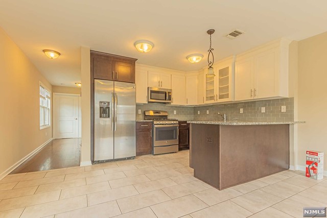 Welcome to Platinum Townhomes! This newly constructed 2,250SF 5-room townhouse offers 3 floors of flexible living space, plus a private 1-car garage and driveway. Ground floor has private entrance from front door and from garage, a half bath, and a den/playroom with sliding glass doors to private patio. Main floor offers a modern kitchen with stainless steel appliances (including dishwasher and large 24.8 cu-ft GE refrigerator) and an open layout with a large dining area, as well as a separate formal living room or potential bedroom/office, and an additional half bathroom. Top floor offers laundry washer and dryer, bedroom, hallway full bathroom, as well as master bedroom and master bath with 2 sinks. Total number of bathrooms throughout the townhouse include 2 full baths and 2 half baths. Interior includes porcelain tiles in both the kitchen and living room with hardwood flooring throughout the rest of the house.