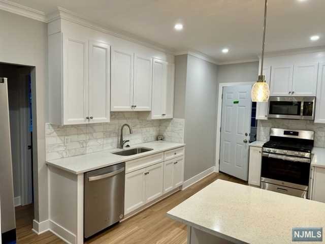 Welcome to this completely renovated two bedroom first floor apartment with 1100 square feet of living space that has been redesigned with an open concept floor plan. This unit features: New Luxury vinyl plank flooring throughout, elegant crown molding in all rooms accenting the high ceilings, heated Sun porch, all new energy efficient vinyl windows, New bathroom with modern polished porcelain tile on walls and shower, new kitchen with 42" shaker-style cabinets, brand new stainless steel appliances, quartz countertops and tile backsplash. Eat-in-kitchen also has quartz countertop breakfast bar. New washer and dryer in basement along with storage space. Step out onto back deck with use of backyard. Short walk to NYC buses and James J Braddock Park. Two off street parking spots included in rent.