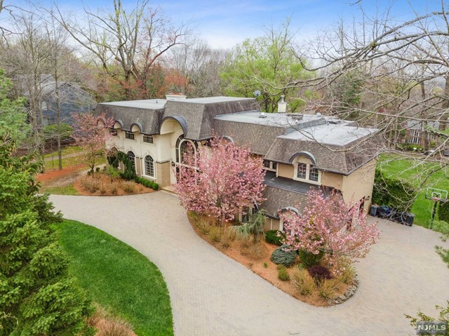 Upon entering this manor style home the 2 story bridle staircase with custom wrought iron railing will take your breath away. The formal living room features a large custom bar which is great for entertaining. As you make your way to the gourmet kitchen with Wolf/Sub zero and Viking appliances you will pass the elevator that services all levels. The upper patio is accessed from the living room and kitchen that offer spectacular views of the perfectly flat yard. All three levels of the home have bedrooms and the master suite includes a terrace, bar area and spa bath. WOW is all you can say about the lower level! Everything revolves around the indoor pool with Jacuzzi. This area also features a gym, party kitchen, full and half bath as well as a Sauna. . When you are not enjoying the pool you can relax in the theatre room with additional bar. Other amenities include a full house generator and luton automated lighting. This is a home resort that must be seen!!
