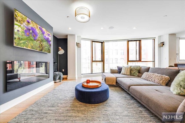 Rarely available, situated in a luxury boutique concrete and steel building in the heart of Hoboken, 718 Jefferson is a sprawling 2617sf residence with keyed elevator entrance, private backyard and garage parking with EV charging provided. This modern floor-through home features 4 spacious bedrooms, 3 baths and a dedicated home office, ideally laid out for families and entertaining with complete separation between open living space and bedrooms. The expansive east facing living area is sundrenched through floor to ceiling, triple glazed windows, with upgraded lighting package, complete with fireplace, and wide plank white oak hardwood floors throughout. A European-style kitchen boasts custom Italian cabinetry, Thermador & Miele appliances, marble backsplash, quartz countertops and a large island with built-in wine fridge. An oversized primary bedroom featuring a massive walk-in closet and en-suite bath with radiant heated floors, Porcelanosa tile, double vanity and soaking tub. Un