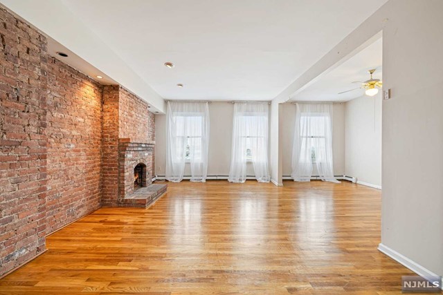 Brownstone living at its finest in the heart of Downtown Newark, this second floor apartment features modern open concept dining and living area, over 9' tall ceilings, exposed brick accent wall, wood burning fireplace, an office / den or optional second bedroom. Huge eat-in kitchen with washer and dryer hookup, updated bathroom with shower over tub and a really good size bedroom. Hardwood and tile throughout (no carpet).Just eight miles away from Manhattan, this unit is a true commuter's dream located within walking distance to Newark Penn Station with direct trains to NYC. Near various shops, Whole Foods, Rutgers University, NJIT, Prudential Center, and just 12 minutes to Newark airport. Easy Street parking (with permit).