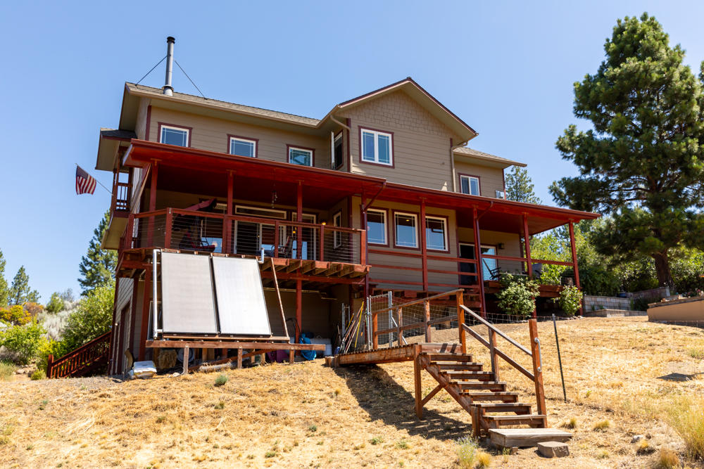 Beautiful custom built 3 bedroom, 2 bath 1849 sf home.  This home sits on 2 spacious acres with incredible views of the lake and mountains. The quality is shown by having radiant solar heated floors and hot water, Italian porcelain tile, Cambria quartz counters, red Travertine & copper slate bathrooms/showers. Covered deck off main floor is perfect for your relaxing and entertaining. Open living room with two stories of custom windows and an upstairs loft for your enjoyment. Master bedroom has a beautiful propane fireplace and a Mitsubishi air conditioner/heater as well as a jetted soaking tub. Current owners seldom have an electricity bill due to the 4.8  Kw Pv solar system  on revenue generating contract. Last year they received more back than they paid for electricity.  Detached wood shed, large insulated finished 952 sf shop/ garage with an upstairs previously used as a music/art room with composting toilet.  Two fenced garden areas plus more than 1/2 acre perimeter fencing.