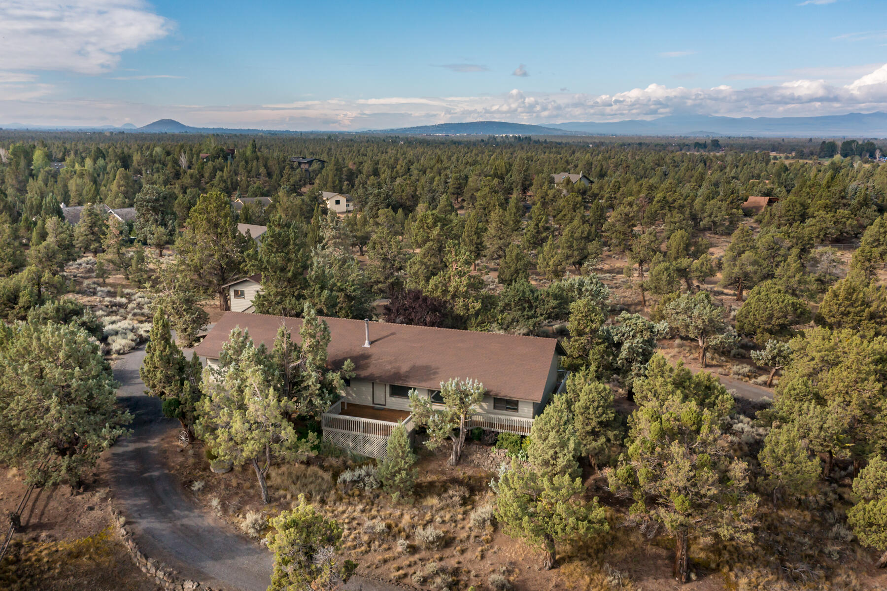 Perched on a knoll along a quiet Boonesborough street, this 2.5-acre property enjoys southwest exposure and sweeping views of the Cascade Mountains. Set on an exceptionally private lot, the home features fresh exterior paint, a wraparound porch, and a versatile floor plan - an ideal canvas for your personal vision. Inside, vaulted ceilings and expansive west-facing windows flood the space with natural light while framing dramatic mountain views and stunning sunsets. The attached two-car garage offers generous storage, complemented by a detached RV/sprinter garage - perfect for a small RV, sprinter van, or boat. Above the garage, a flexible bonus space is ideal for a home office or quiet retreat. The property itself feels like a sanctuary, with abundant wildlife, space for horses, and a sense of privacy rarely found so close to town. Boonesborough is known for its peaceful setting, large lots, and access to outdoor recreation - all less than 20 minutes from both Bend and Redmond.