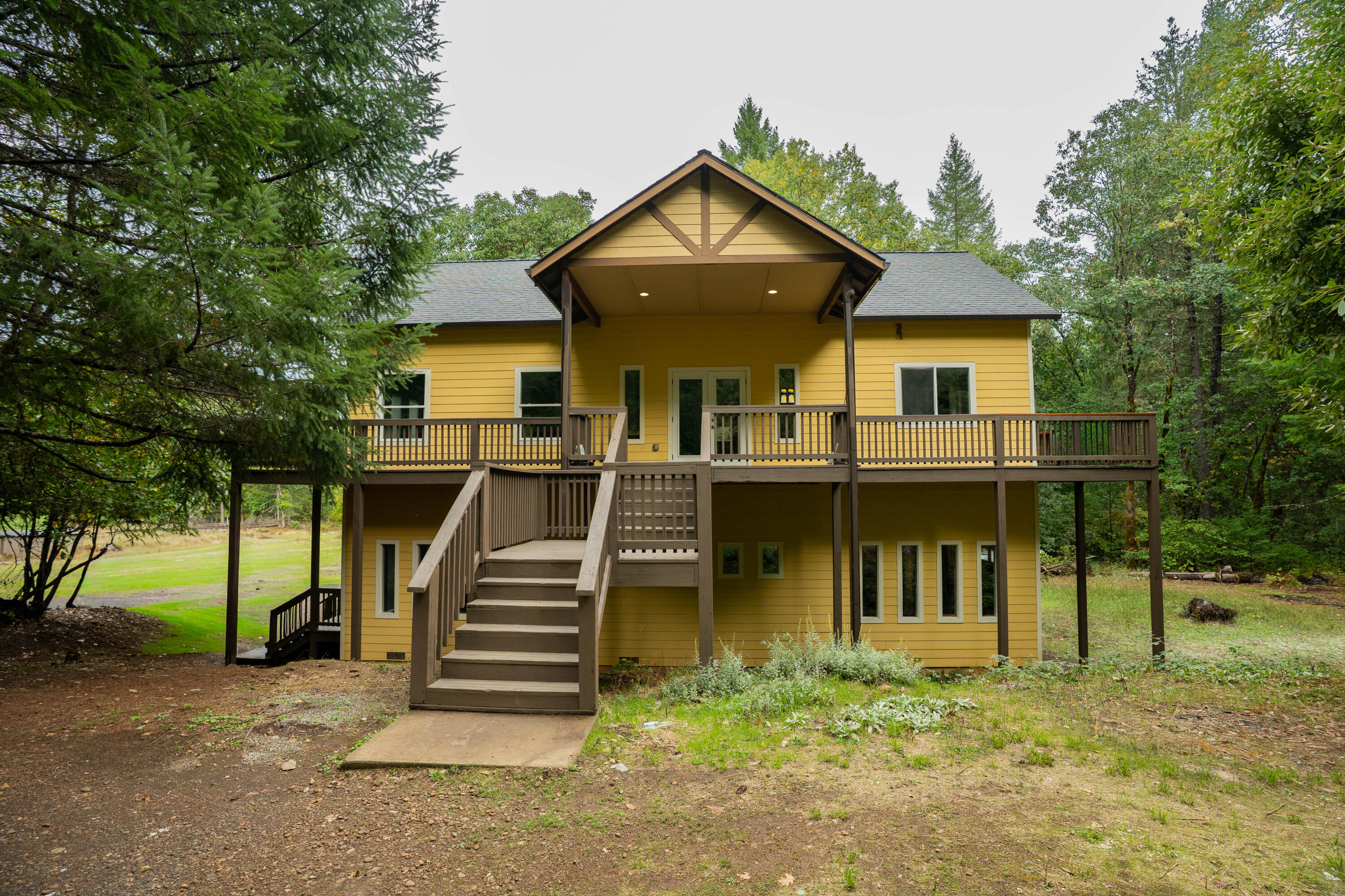 Nestled on five serene acres in the heart of the Illinois Valley, this beautifully designed two-story home offers both privacy and natural light in abundance. With 2,784 square feet of thoughtfully planned living space, the home features three bedrooms and two and a half baths. The main level welcomes you with an open floor plan, a spacious family room, a convenient half bath, and an oversized laundry and mud room that adds function and charm. Upstairs, two bedrooms share a Jack and Jill bath while the primary suite offers a private retreat surrounded by treetop views. Expansive windows frame the surrounding landscape, creating a seamless connection between indoor comfort and the peaceful outdoors. With room for gardening, recreation, or quiet reflection, this property embodies the best of rural living just a scenic drive to Grants Pass and the Rogue River.