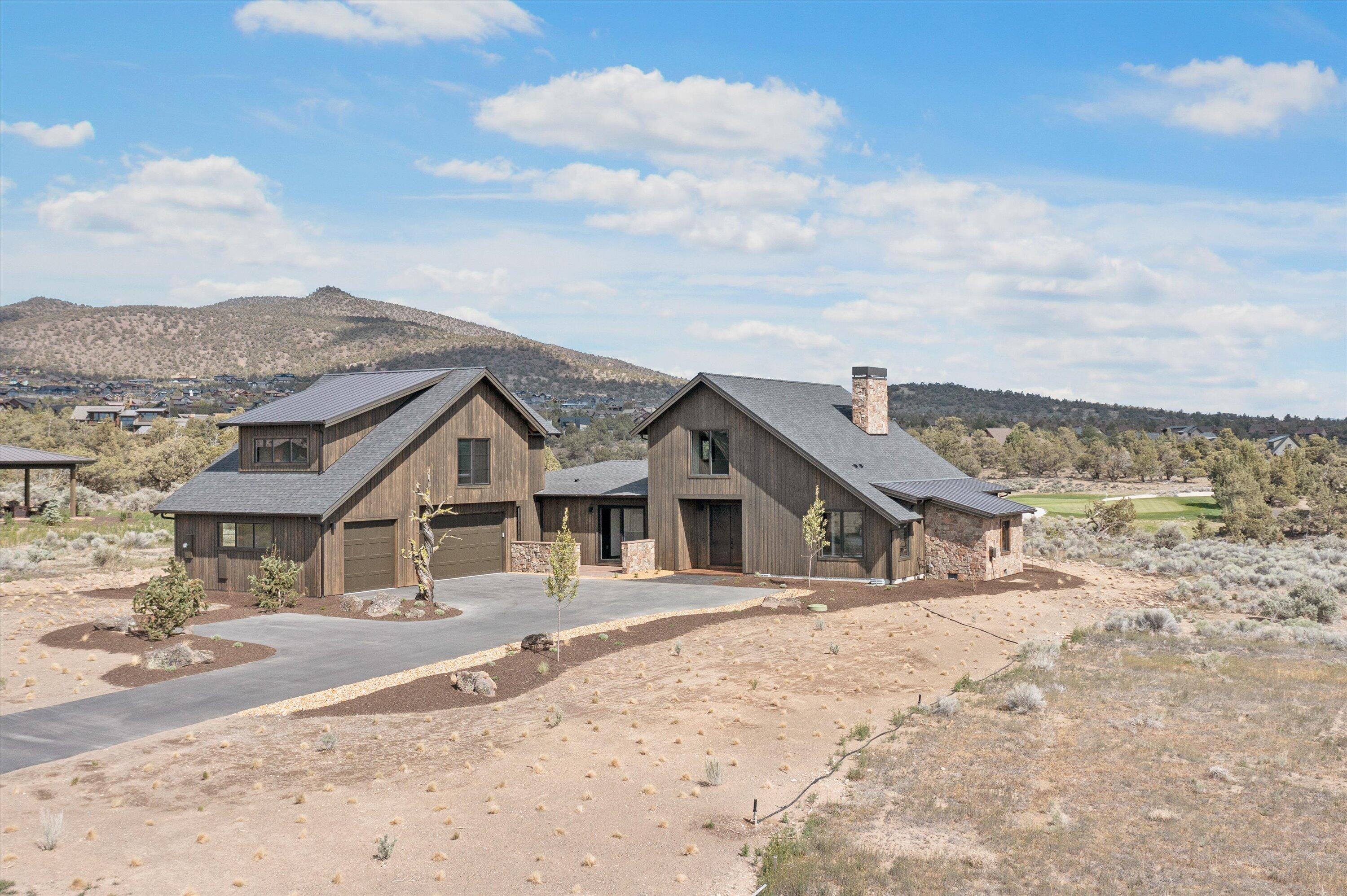 Beautiful two story ranch-style home accentuated with stone accents and stained wood siding on the exterior. Striking views of the 17th Green and Powell Buttes out the back and sweeping Cascade Mountain views from the front patio of this new construction home. 
Inside, you are greeted by a spacious great room with vaulted ceilings and beautifully crafted built-ins in addition to an expansive dining room area. This very open floor plan boasts features, a kitchen with a large slab island that is perfect for entertaining. The primary bedroom is conveniently located on the first floor with a large walk-in closet, oversized soaking tub and spacious shower. There's also a den ideal for an office or guest room that opens onto a paved courtyard, two additional bedrooms, with a full-sized bathroom. A utility room and oversized three-bay garage finish the first floor. 
On the second floor you will find a large bonus/media room that offers tremendous Cascade Mountain views from multiple window