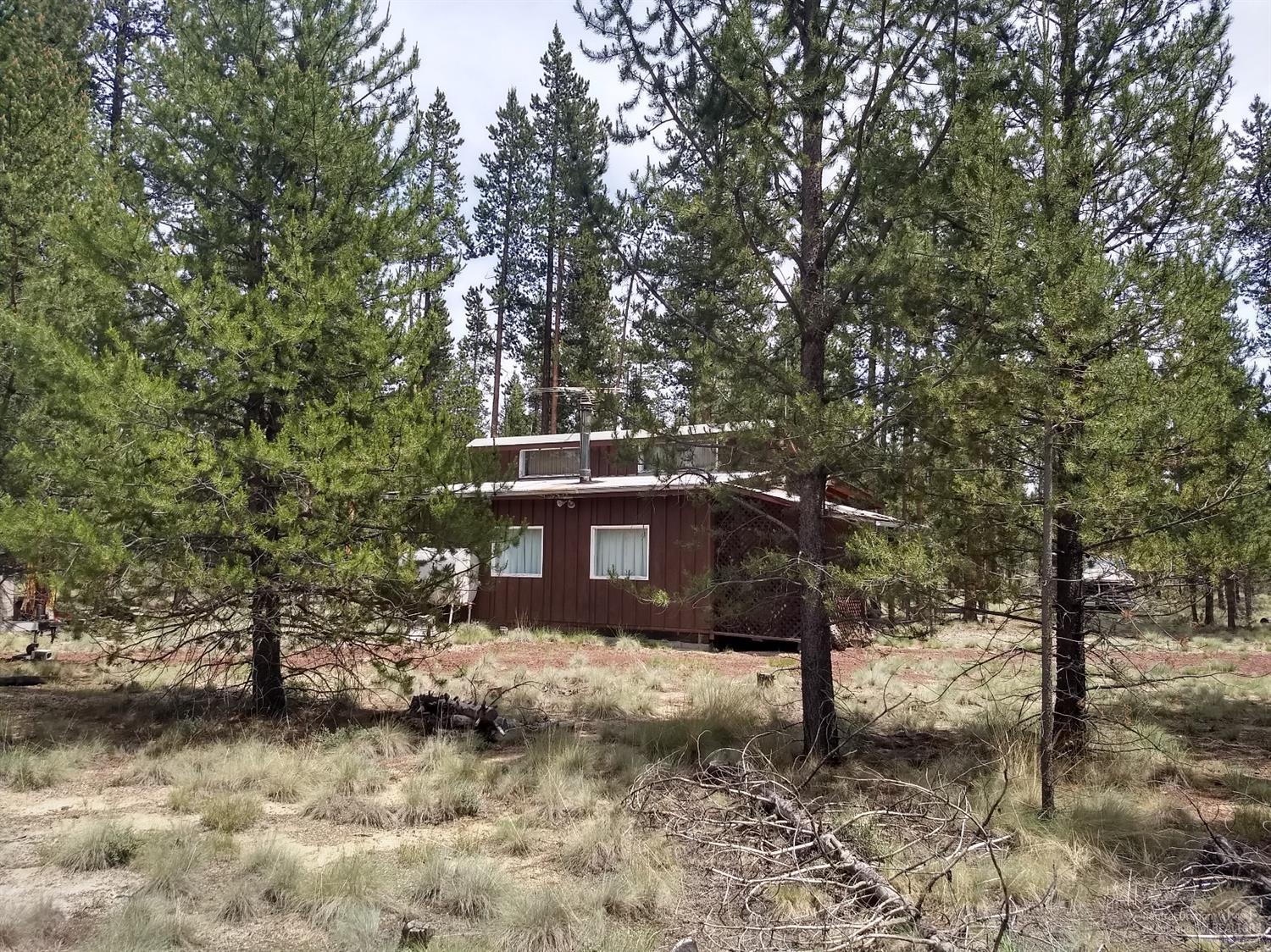 Great treed property to build your dream home or use the existing rustic one room cabin with kitchen area and bathroom. Covered porch and attached carport. There is a well and septic, 1000 gal concrete tank, on the property (buyer to do due diligence on these). Solar panels were used for electricity. Power is at the road. Public lands are nearby for all your outdoor activities.