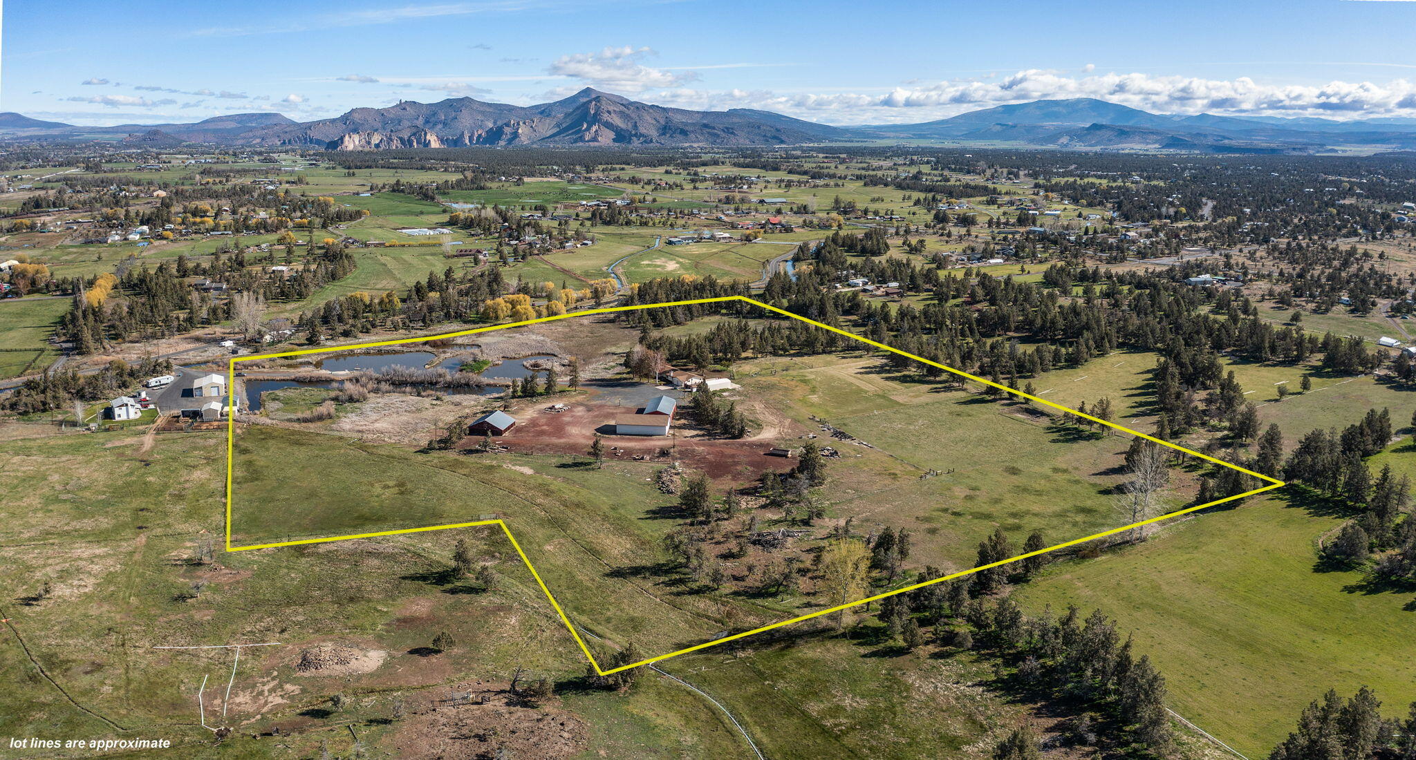 Situated outside of Redmond city limits, this 26.97-acre property is set off the road and offers so much privacy. 20 acres of COID irrigation and Cascade Mountain views from this charming property. You'll see plenty of waterfowl over the small bridge straddled with ponds on both sides. This lovely single-level ranch is 2374 sq ft and is move-in ready. A spacious kitchen and dining area with views of fruit trees and acreage. The living room has a wood stove insert and wood beams on the ceiling. Down the hall, there is a primary bedroom with a walk-in closet and bathroom and 3 other bedrooms. The parcel has two large shops, a smaller shop, and a barn with plenty of room for equipment, vehicles, and toys. Fenced and enjoy pear and apple fruit trees. Just minutes to stores and shops in NE Redmond. New well as of 2023 and new exterior paint as of 2024.