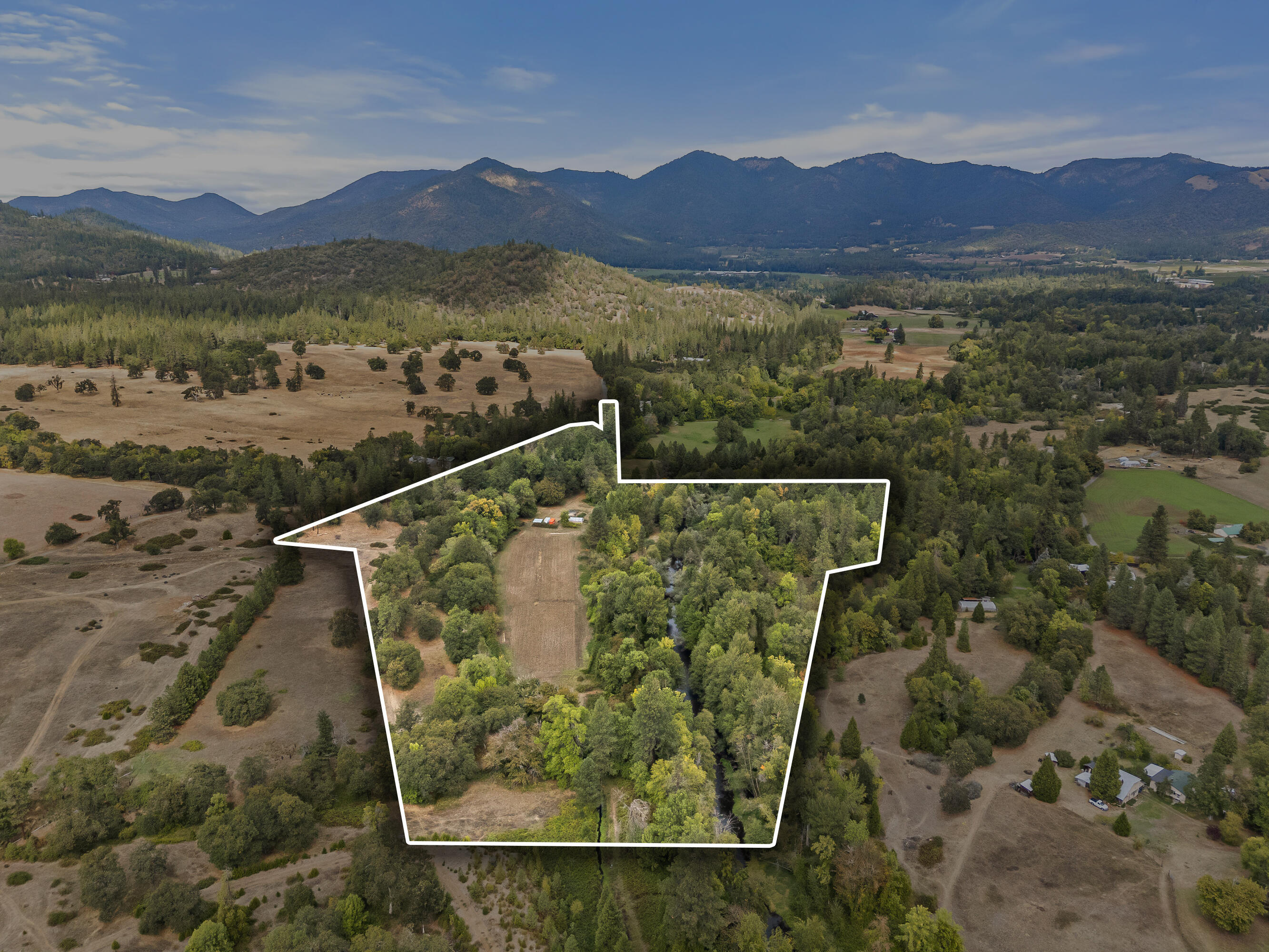 Rare Find in the Applegate Valley, Custom, Cedar home  w/ 1/3 mile of Williams Creek frontage traversing through this irrigated farm land. 33.3 ac. w/ 10 acres in water rights. 2 tax lots. Property is adjacent to Pacifica Gardens known for it's environmental education. Mostly level land with established organic gardens & orchard. Been used as a Certified Organic seed farm. Farming features 2 green houses, 3 separate fields, fenced & cross fenced. After a day in the sun enjoy the dipping pond for a cool down or wander along the tranquil creek trail. The 2 car garage/shop has been used for seed storage and processing, 2nd story has open living w/ separate office room. Home is open concept w/ solar tubes, French doors to patio off the living room. Kitchen offers a cook woodstove, custom Myrtlewood breakfast bar and large pantry. Separate utility canning room w/ farm sink. Bedrooms open to back deck. Wood floors throughout made out of Chinkapin and Myrtlewood. Lower level has root cellar.