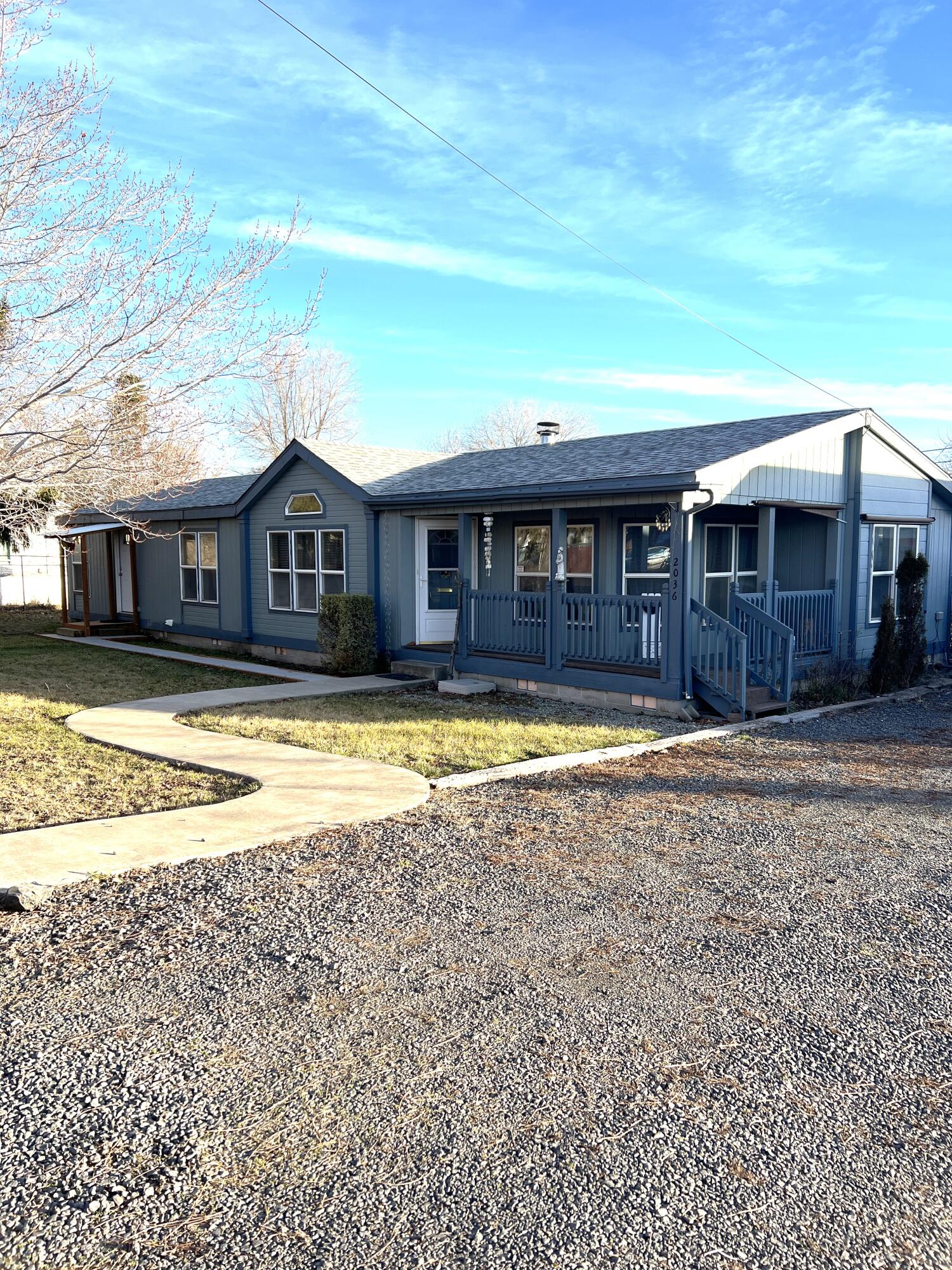 This adorable and well-kept 3 bedroom, 2 bath manufactured home on three city lots is a must see. This move in-ready house has a great sized yard with nearly 1/2 an acre, a 30'x30' detached shop-garage, and some nice updates. A separate entrance has been created into the primary suite and the primary bathroom has been nicely updated with a new tub and toilet and it has a separate shower. New laminate flooring has been installed in living room, dining room, hallway and primary bedroom/bathroom.  New flooring in hall bath and most lights and fixtures have been updated. There is a pellet insert but it needs a new panel board. This home is close to a main bus line, shopping, and eating establishment.