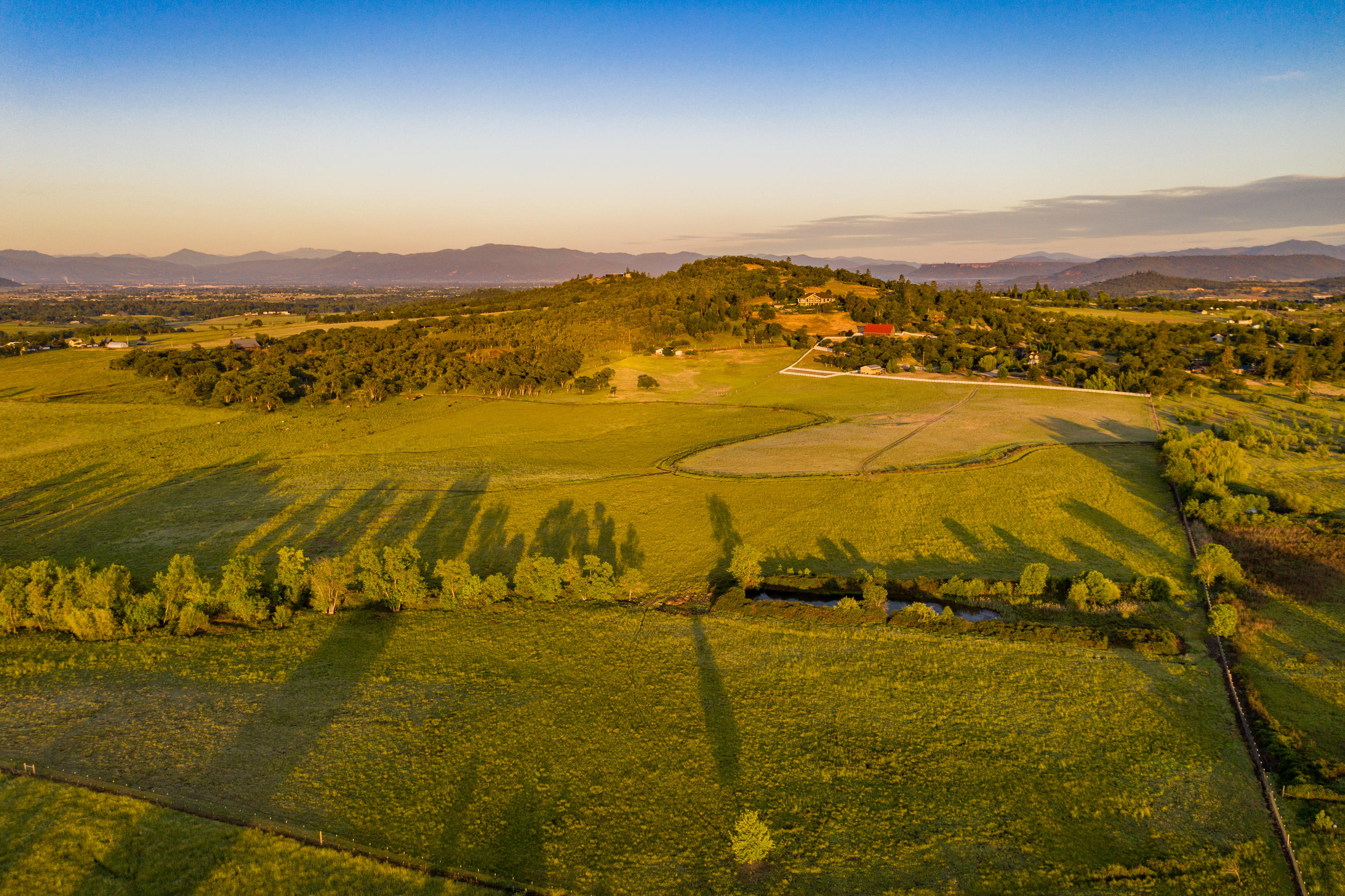 Welcome to Stevens Road Ranch, featuring incredible views, convenience to town, two beautiful residences, a historic barn, shop, oak savannahs, pasture, & 37 irrigated acres. Facing Mt McLoughlin, this extraordinary property provides the perfect balance between the expansive beauty of rural life and the delights of modern living. The main home boasts over 3,000 square feet of high-end finishes, with an open floor plan, grand vaulted ceilings, spacious living room and well appointed chef's kitchen. A lavish master suite with Italian marble, 2 guest bedrooms, laundry room, & guest bathroom round out the main level.  Upstairs is the large recreation room and full bath. Surrounded by charming floral plantings and stunning maples, the outside living space includes 2 patios, slate flooring, & water feature. The 1,700+ SF log cabin has an inviting 3 bed, 3 bath floor plan, large wrap-around deck and great views. Just 2 miles to Eagle Point and 12 miles to the Medford International Airport.