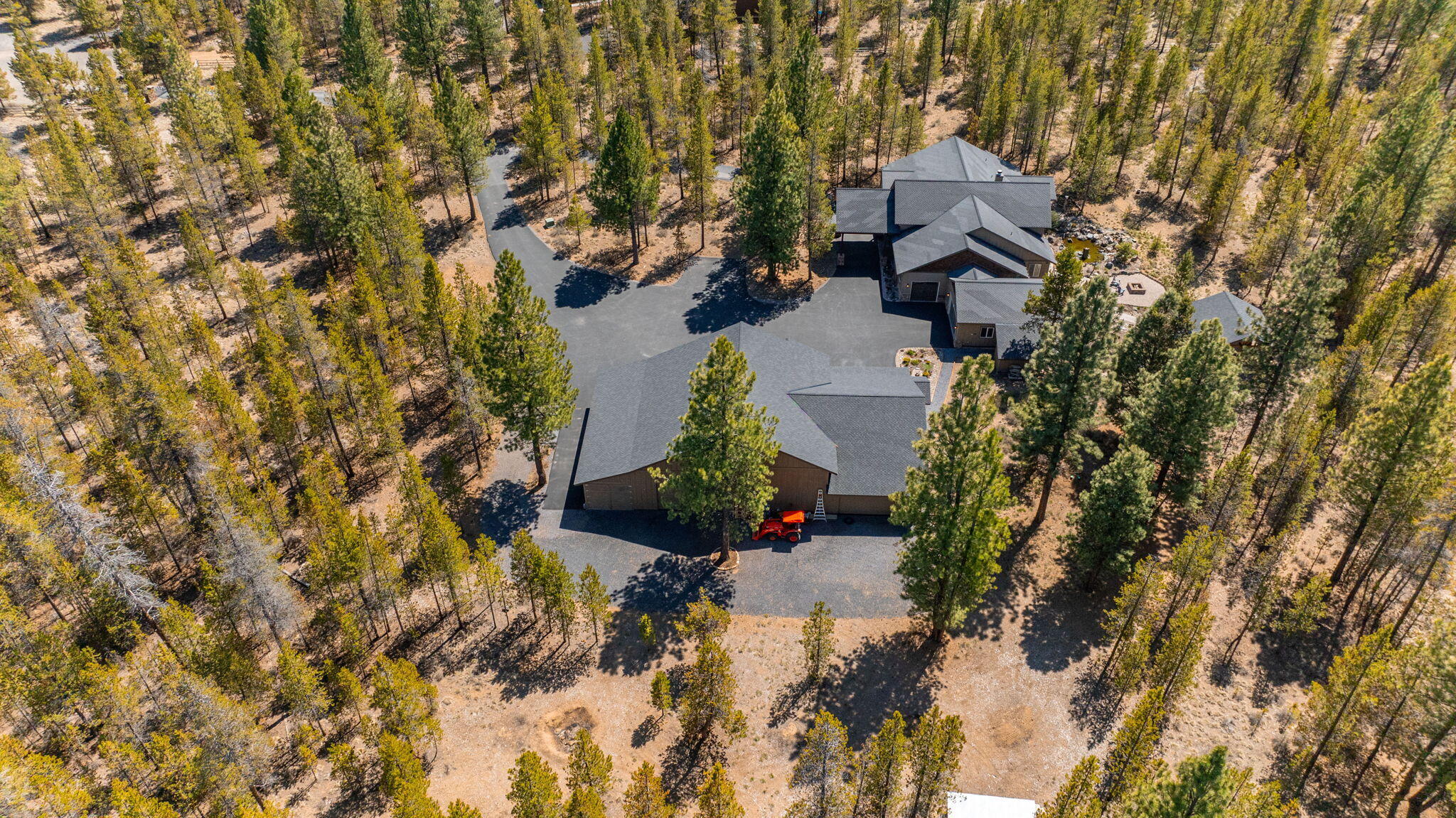 Experience this single-level custom home  on a gated, wooded homesite backing to public forest land.  Featuring three bedrooms and three full bathrooms, including two en-suites. The great room is the centerpiece, with vaulted wood ceilings, open beamed trusses, and an Extraordinaire wood burning fireplace with a floor-to-ceiling rock surround with integrated cabinetry overlooking the outdoor water feature in the backyard. The primary suite is a retreat within itself, featuring a custom built-in dresser, fireplace, and a spa-like bathroom with an infinity tub, heated floor and a walk-in tile shower. Step outside to indulge in a fully equipped and covered outdoor kitchen with kegerator, fireplace, and TV, and a generous workshop with a 4+ car drive-through garage bay, an RV bay, and a drive-through mechanic's bay all with epoxy-flooring, and built-in cabinetry. Relax next to the serene water feature, unwind in the hot tub, or enjoy the starry night sky by the fire pit.