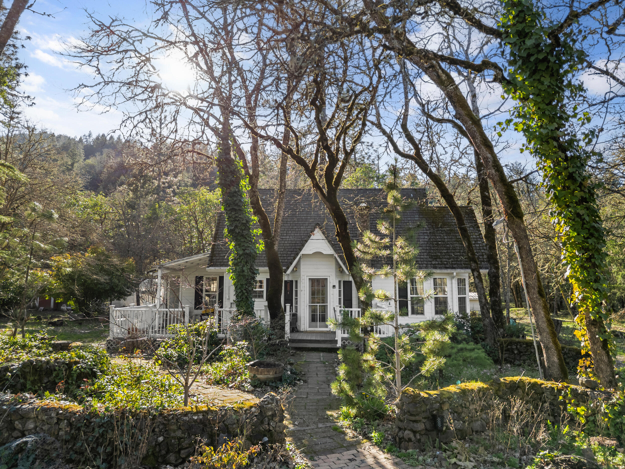Welcome to this truly enchanting 3-bed/1-bath cottage nestled in a breathtaking storybook setting. Situated on a serene 1-acre lot, this adorable home exudes warmth, character, and timeless charm. From the moment you arrive, you'll be captivated by the picturesque surroundings, mature trees, and lush greenery that create a private and peaceful retreat. Inside, the cozy living space is filled with natural light, highlighting the home's inviting ambiance. The well-appointed kitchen offers functionality with a touch of rustic charm, while the comfortable bedrooms provide a restful haven. The bathroom is thoughtfully designed to maximize space & comfort. Step outside to enjoy the tranquil beauty of the expansive yard—perfect for gardening, entertaining, or simply unwinding in nature. Located just minutes from town yet offering a secluded feel, this charming cottage is a rare gem.
