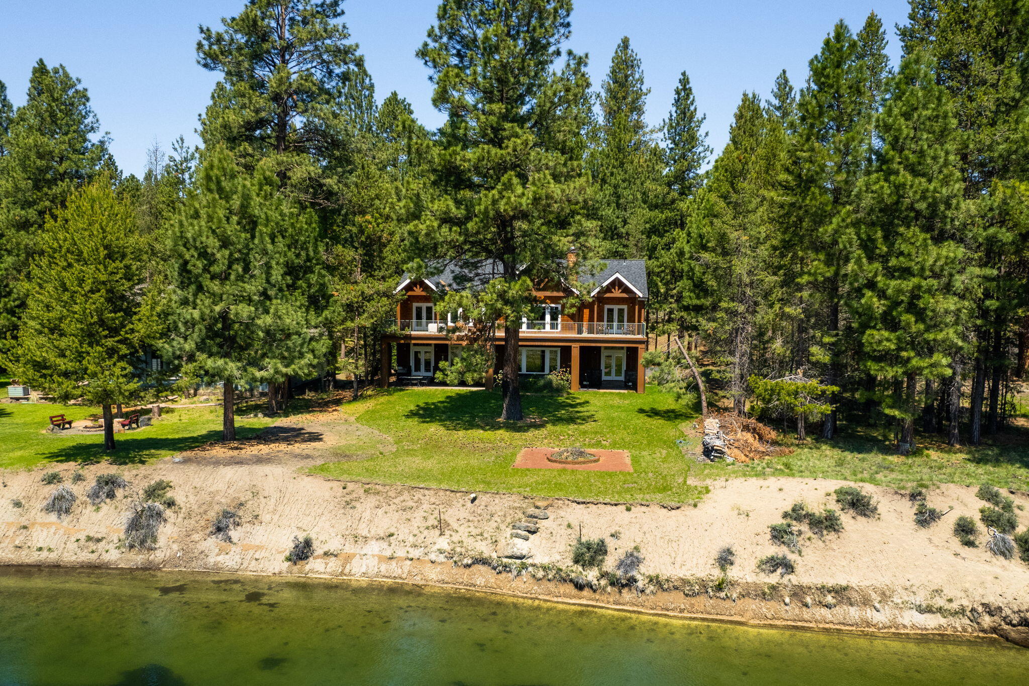 A legacy riverfront estate that captures the very essence of Central Oregon's natural beauty! Equal parts grandeur and comfort, this home makes a striking first impression with soaring ceilings, travertine floors, and an impressive spiral staircase. Enjoy views of the Deschutes River beside the two-story fireplace in the great room, or settle into the kitchen where you will find custom cabinetry, honed granite countertops, luxury appliances, both formal and informal dining areas as well as a pantry, wine bar, and so much more. There is no space left unimagined in this tastefully appointed home which offers a primary sanctuary that opens to an expansive second story patio, a main floor ensuite for guests, two additional guest bedrooms, an office or den, media room with bar for game days and movie nights, bunk room for sleepovers, open reading loft, and expansive 3 car garage. Designed for fun, gathering, and festivities, this is the home to build enduring memories.