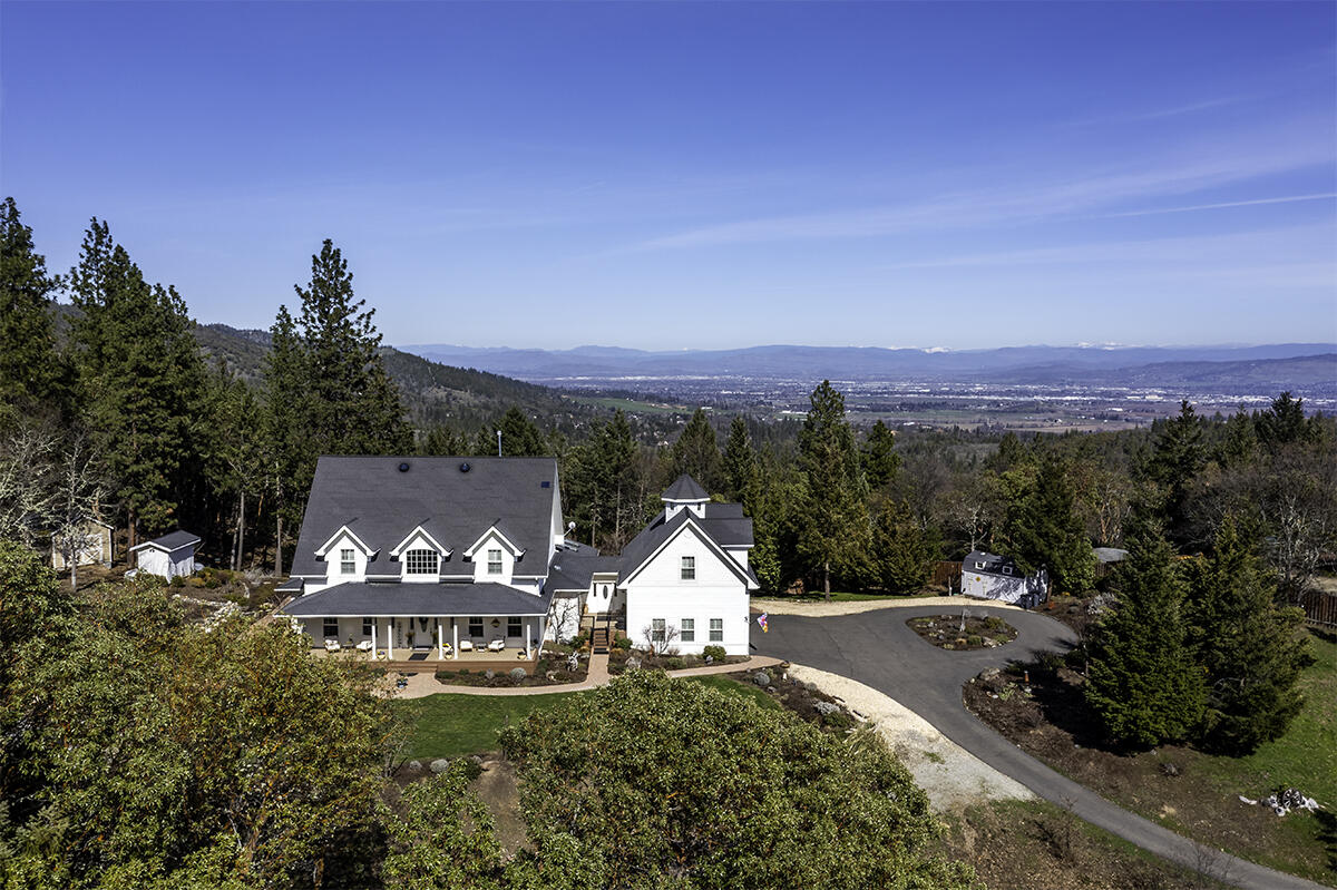 Stunning contemporary farmhouse w/breathtaking mountain views, nestled in the scenic hills of historic Jacksonville! Set on 10.02 acres, this gated 4,123 sq. ft. estate offers unparalleled privacy & seclusion while being just minutes from downtown shopping, Britt Festival, renowned wineries & more. Recognized as a National Firewise USA site, this stunning 4 bed, 3.5 bath home features two primary suites, including one conveniently located on the main level. Elegant foyer showcasing a grand staircase, soaring ceilings, rich hardwood floors & exquisite crown molding throughout. The gourmet kitchen seamlessly flows into the living & dining areas, boasting a butcher block island, Thermador range & a Butler's pantry w/wine refrigerator. Office with convenient built-ins, plus a finished bonus area above the 3-car attached garage. Park-like landscaping, charming covered front porch, rose gardens & flagstone patio w/fishpond & waterfall. Spacious deck w/exterior kitchen, BBQ.