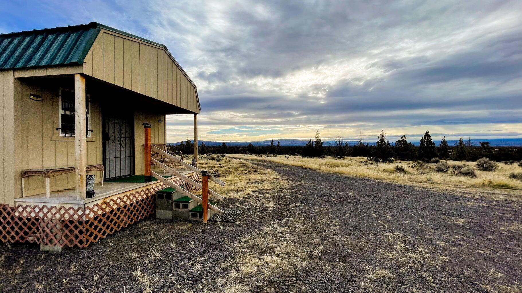 Escape to your own 160-acre off-grid retreat with panoramic views of the Three Sisters, Mt. Bachelor and Crooked River Basin. This private property includes a fully furnished 700 sq ft cabin powered by solar with generator backup, 2,300-gallon cistern, septic, and a solar-powered gate with perimeter fencing. Relax on the covered porch, explore miles of open range, or ride directly onto 75,000 acres of adjacent BLM land and OHV trails. Just 11 miles from Prineville and 30 minutes to Bend, this self-sufficient getaway blends solitude and convenience—perfect for recreation, hunting, or simply unplugging. Infrastructure is in place and move-in ready, offering a rare chance to own Central Oregon wilderness with comfort already built in.