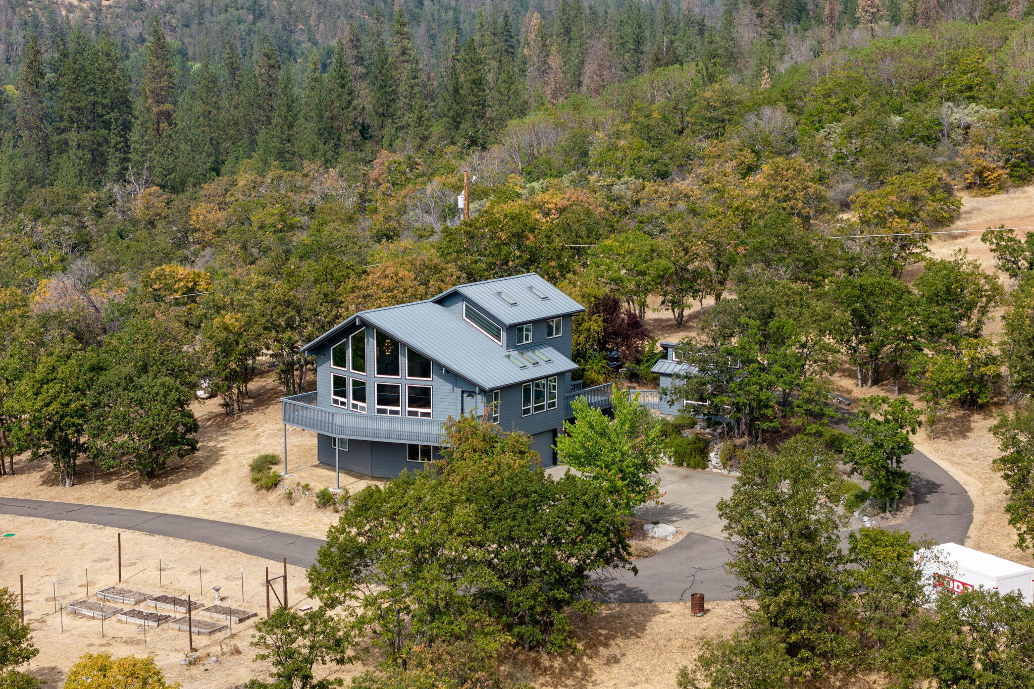 Beautiful custom home sits on 10 acres, including the adjoining but separate legal 5 acre parcel! Private setting with fantastic views, yet only minutes to historic Jacksonville! Custom features 18+ foot vaulted ceilings, large windows for great natural lighting, mudroom, central vac, hardwood floors and metal roof. Great room offers mountain views to watch hang & paragliding! Large kitchen has abundant cabinetry, tile counter tops, propane range, and eating bar. Lovely primary bedroom with fantastic views, skylights, walk-in closet, primary bathroom has tile floors & large shower. Great laundry room with new LG washer and dryer. Over-sized 3-car climate controlled garage offers a workshop plus a finished office/den and wired for backup generator. Outbuilding w/sink, garden beds, chicken coop, tons of use-able land, and open space. Paved driveway with gated entrance. Just minutes to hiking and biking trails, BLM land, wineries, shopping and restaurants in historic Jacksonville!