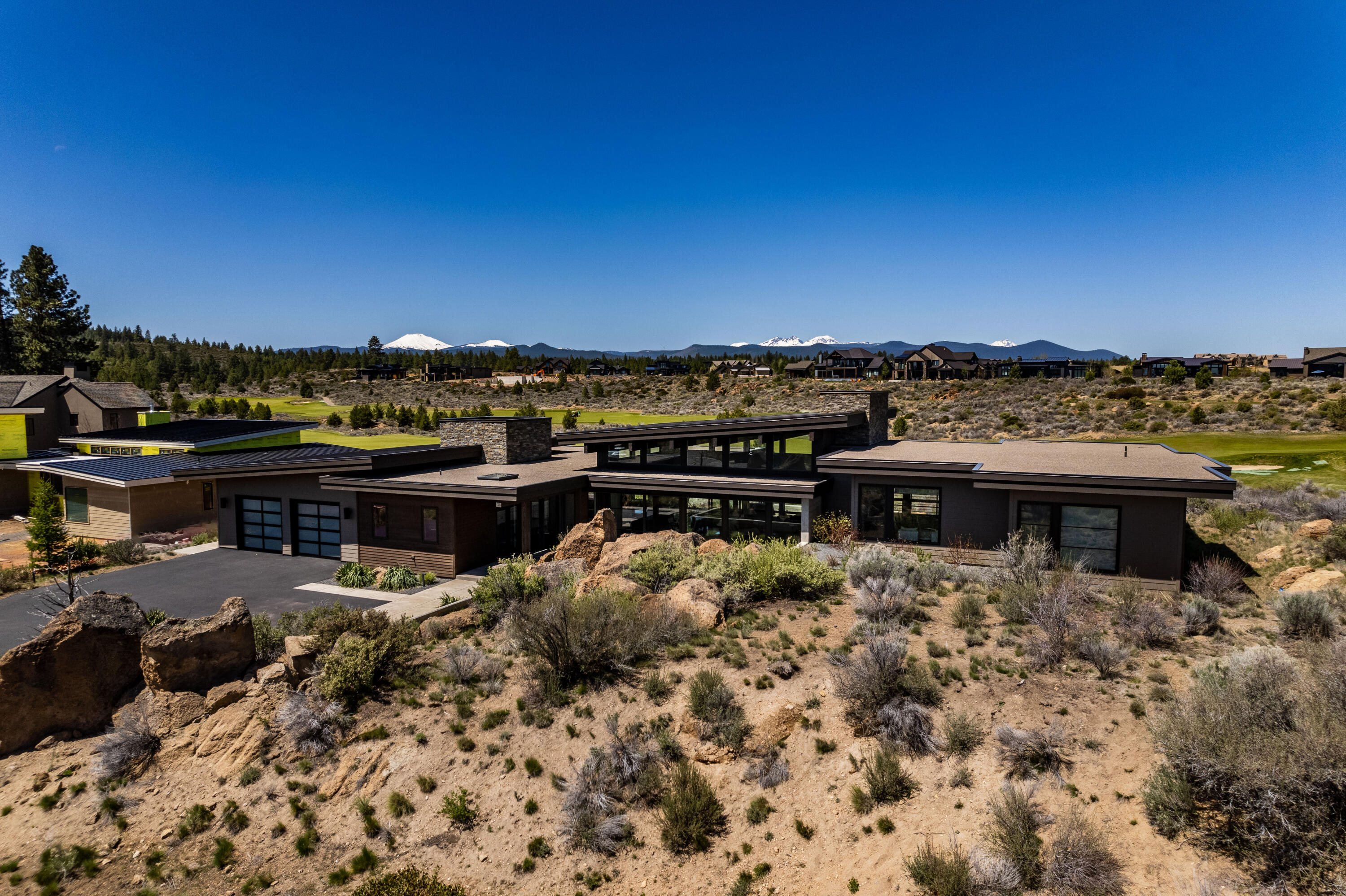 Situated on Tetherow's 4th fairway with incredible views of the Cascade Mountains, this one level, high end, custom built home by renowned High Timber has an excellent floor plan, abundance of natural light, soaring ceilings, and designer details and finishes. Located on a private gated cul de sac and thoughtfully designed to create an indoor/outdoor ambiance with perfect sun orientation creating a soothing retreat from every room. Features include stainless appliances, automated sound lighting & curtains, outdoor shower, in-ground hot tub, gas fire pit,  floor to ceiling windows, and a large great room.  This thoughtful floorplan also offers 3 Bedrooms, 3.5 Baths, a Bonus Room and an Office.