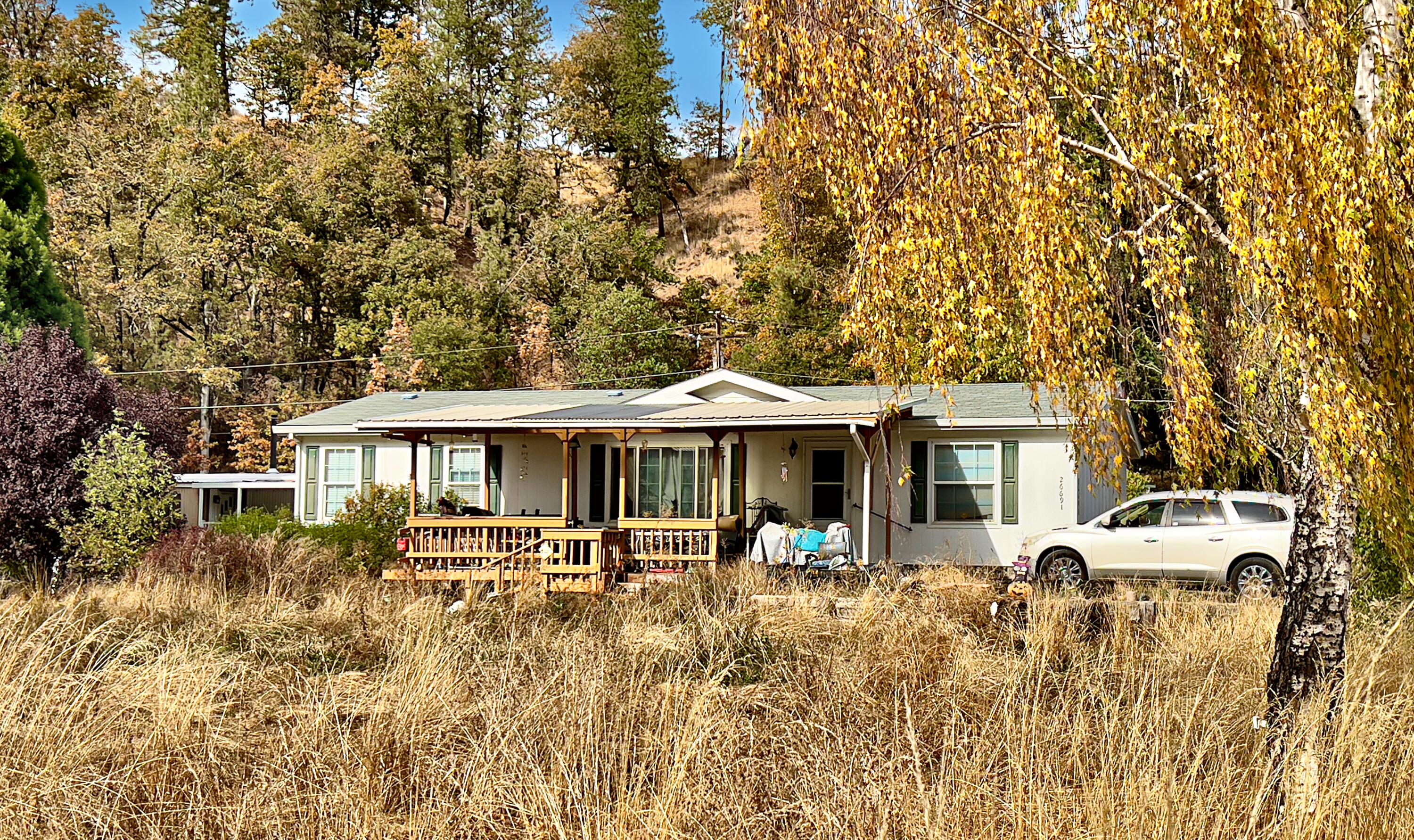 ACREAGE, ''SHOP'' w/ADU POTENTIAL, CARPORT w/RV METER, WOW! Spacious 3bd/2ba manufactured home with covered porch on mostly level acreage.  Split floor plan offers a primary suite with oversized soaking tub, dual vanities and a separate shower. Vaulted living spaces with ceiling fans; laundry room/mudroom. The wood framed workshop with glass slider may potentially convert to an ADU or additional finished area (inquire with county; workshop was remodeled from a previous ''old house'') The upper detached metal carport has an RV meter and the lower carport is adjacent to a shed; there's ample room for storage and plenty of parking for RV, boat, trailers & toys. Property features multiple sheds/storage outbuildings, a fire-pit, even an older hot tub. Property is partially fenced. New 2000 gallon holding tank and pump installed 10/2021, new well pump & pipeline in 2022. Home has ''short sale conditions''; inquire with listing agent for details.