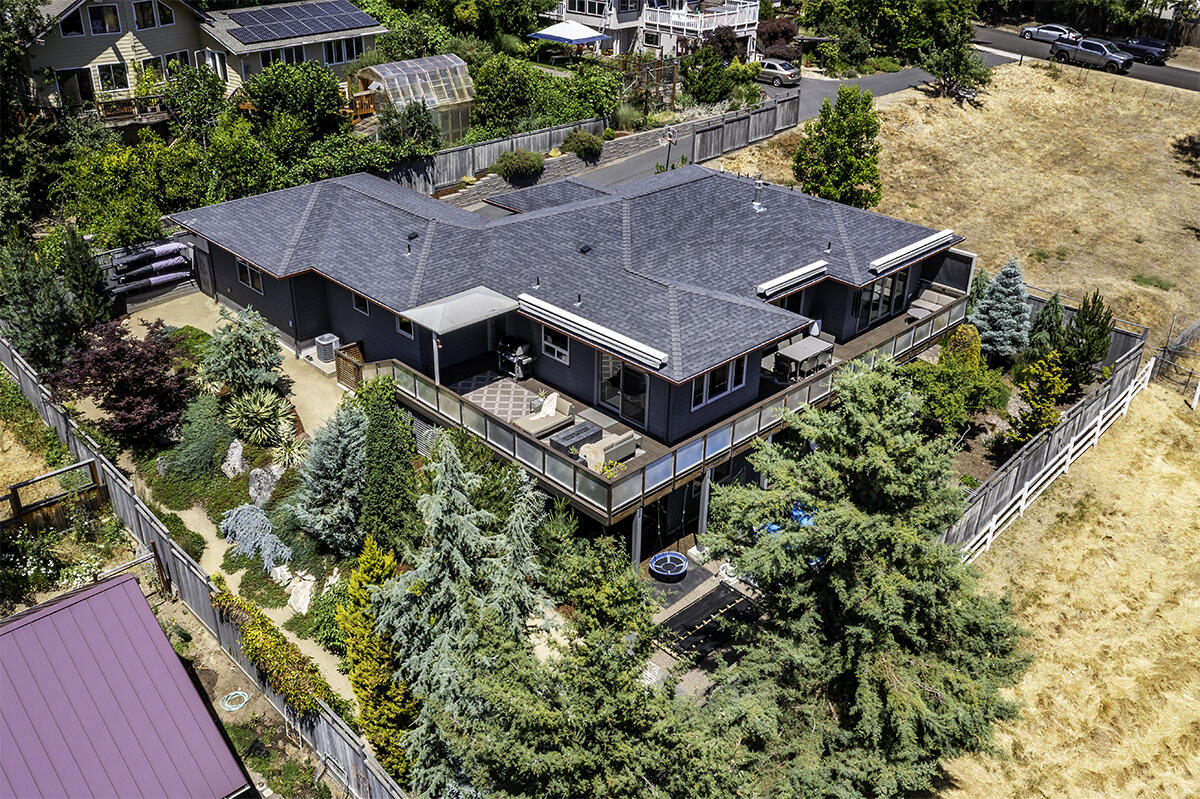 Gorgeous, architecturally designed contemporary home nestled in the hills of Ashland, Oregon. This sophisticated 3 bed, 2.5 bath is beautifully appointed w/luxury systems & upgrades throughout including hardwood floors, designer lighting & floor to ceiling glass doors. Main level primary suite w/private deck access, ceiling treatments & spa like ensuite featuring a floating dual sink vanity, walk-in shower, tile floors & freestanding soaking tub. Chef's designer kitchen equipped w/a commercial grade hood fan, Thermador 6 burner range w/double ovens, expansive quartz waterfall island & full height penny tile backsplash. The lower level includes 2 bedrooms, a bonus room, full bathroom & family room plus an elegant, temperature-controlled wine room.  Dedicated laundry/mud room & a formal office area outfitted w/a commercial grade glass door. 2-car garage w/storage & EV hookup. Oversized .26-acre lot w/tons of privacy, easy-care landscaping & fantastic views of the surrounding mountains!