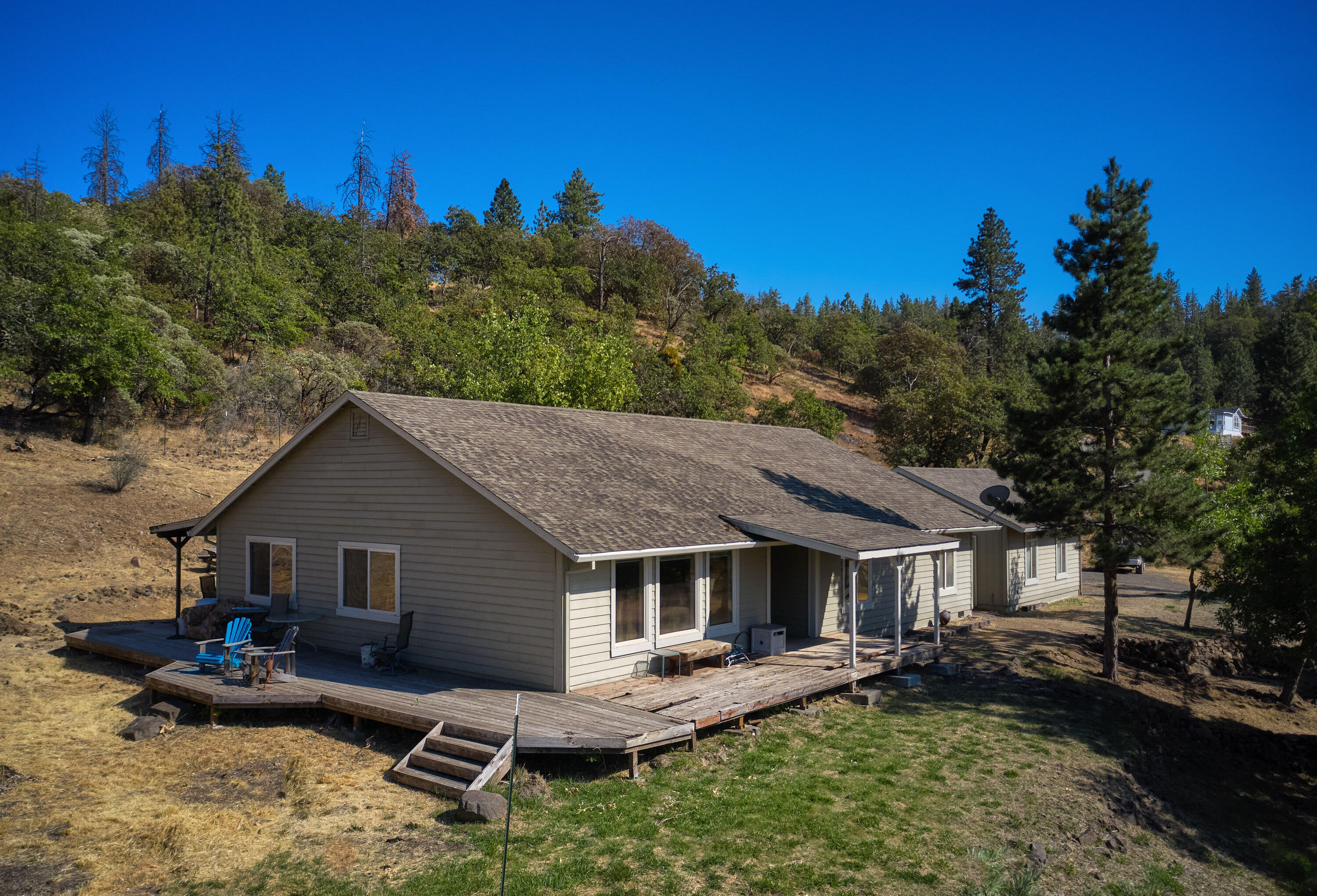 Mountain View Home on 7.7 Acres - Cash Only. Welcome to this 3-bedroom, 2-bathroom home with serene mountain views and room to make it your own. With 1,920 square feet, this home features vaulted ceilings in the living room and kitchen, creating a bright and spacious atmosphere. The living room and dining areas have beautiful hardwood flooring along with tile in the entry and kitchen for added style and durability. The primary bedroom is exceptionally sized, featuring a large walk-in closet plus additional closet space. Outside, you'll find a detached two-car garage, an outbuilding, and wide-open space to explore. Set on 7.7 acres with a mix of open land and tree-lined hillside, the property offers privacy and serenity. An electronic gated entry provides added security and convenience. Cash only—this home needs some work and is not financeable.