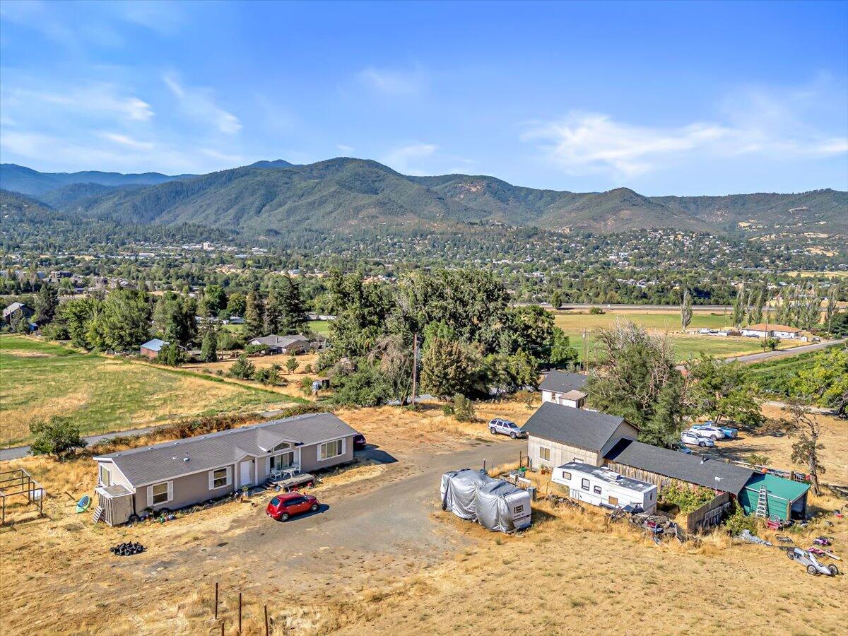 Breathtaking views and endless potential! Overlooking downtown Ashland, this level, 4.15-acre property offers panoramic views of the city lights and surrounding mountains. The 3-bedroom, 2-bath manufactured home (2005) with split bedroom and open floor plan, features 1,728 sq ft of comfortable living space, vaulted ceilings and so much natural light.  Enjoy peaceful rural living just minutes from town—with irrigation rights, this property is ideal for a mini-farm or horse setup.  Sunrises are beautiful, and enjoy sunsets off the back porch and watch the lights of Ashland come up!  Additional structures include the original 1936 home, which may be used as office space per Planning Department guidance, also Barn conversion with a bathroom added in 2010—perfect for storage, workshops, or creative projects. Buyer to perform due diligence on all potential uses.  So many possibilities—bring your vision and make this unique Ashland property your own!